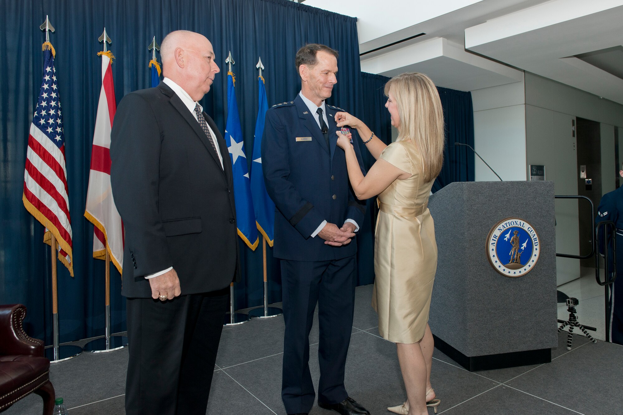 Rebecca Weaver Clarke fastens the retirement pin to the uniform of her spouse, Lt. Gen. Stanley E. Clarke III during his retirement ceremony at the Air National Guard Readiness Center, Joint Base Andrews, Md., December 18. 2015. Clarke is the 15th director of the ANG and retired after 34 years of service. (Air National Guard photo by Master Sgt. Marvin R. Preston/Released)