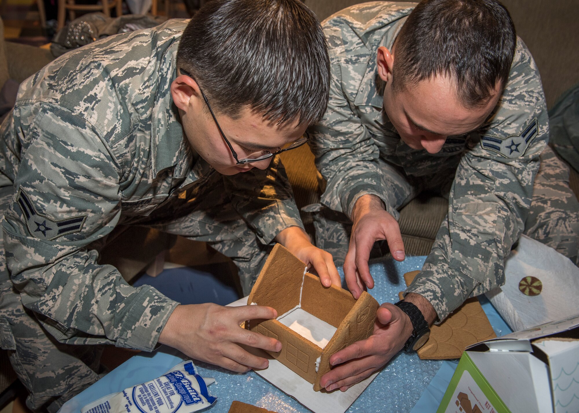 PETERSON AIR FORCE BASE, Colo. – Airmen 1st Class Beterdene Badrakh and David Uribe, 4th Space Operations Squadron, work together to create a sturdy foundation for their gingerbread house Dec. 16, 2015 at the Eclipse Café. The Peterson Chapel held their annual Gingerbread House Building Competition for Airmen to come together and enjoy some holiday fun. (U.S. Air Force photo by Senior Airman Rose Gudex)