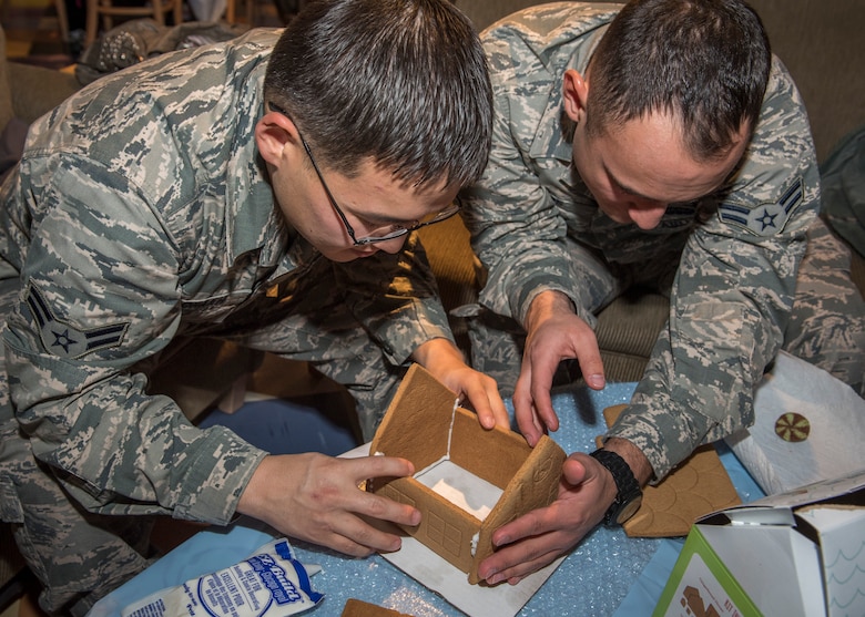 PETERSON AIR FORCE BASE, Colo. – Airmen 1st Class Beterdene Badrakh and David Uribe, 4th Space Operations Squadron, work together to create a sturdy foundation for their gingerbread house Dec. 16, 2015 at the Eclipse Café. The Peterson Chapel held their annual Gingerbread House Building Competition for Airmen to come together and enjoy some holiday fun. (U.S. Air Force photo by Senior Airman Rose Gudex)