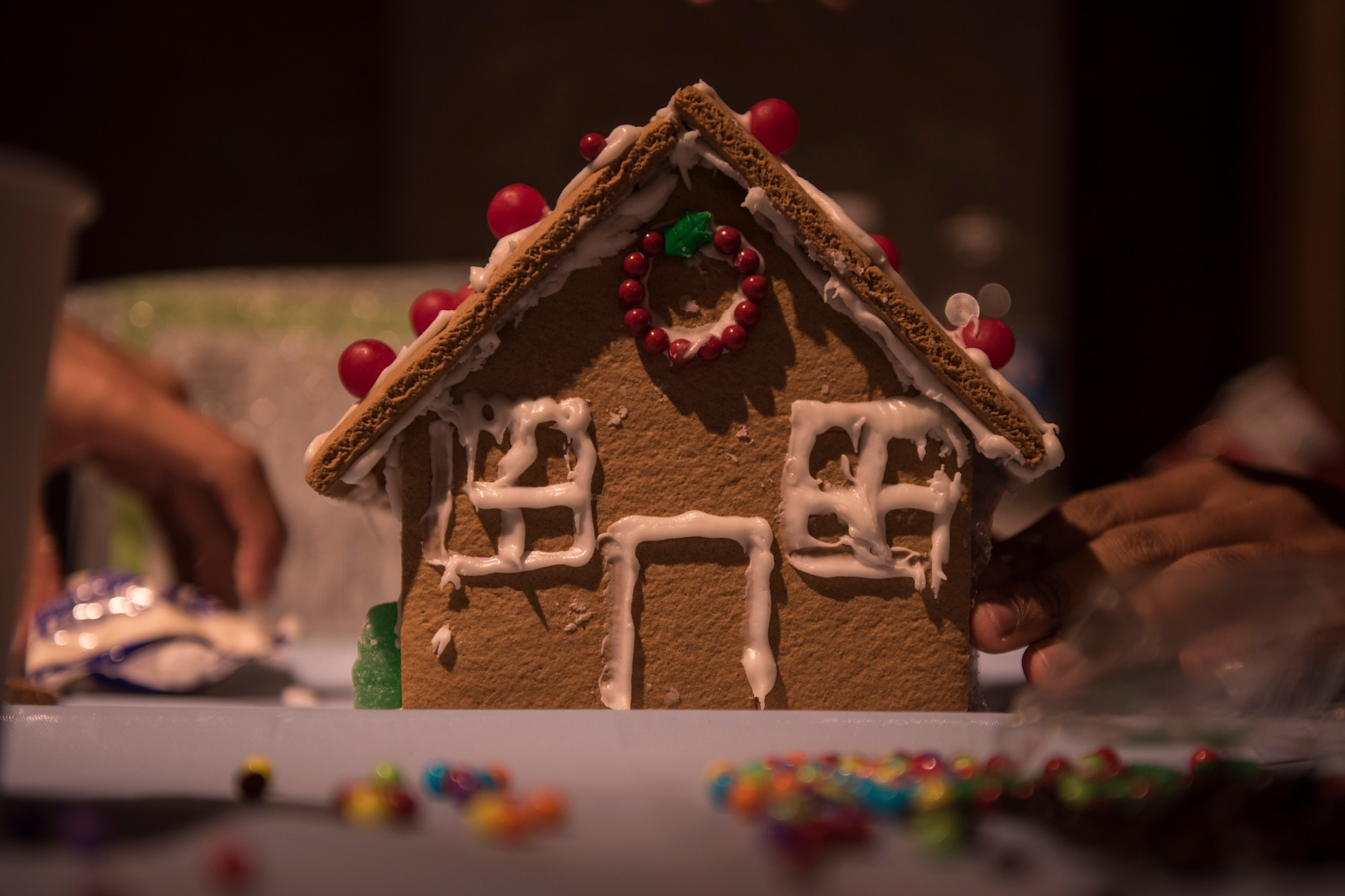 PETERSON AIR FORCE BASE, Colo. – Airmen from the 21st Medical Group create a gingerbread house during the Gingerbread House Building Competition hosted by the Peterson Chapel at the Eclipse Café on Dec. 16, 2015. The chapel provided all supplies, however builders could bring extra candy to use on their house. (U.S. Air Force photo by Senior Airman Rose Gudex)