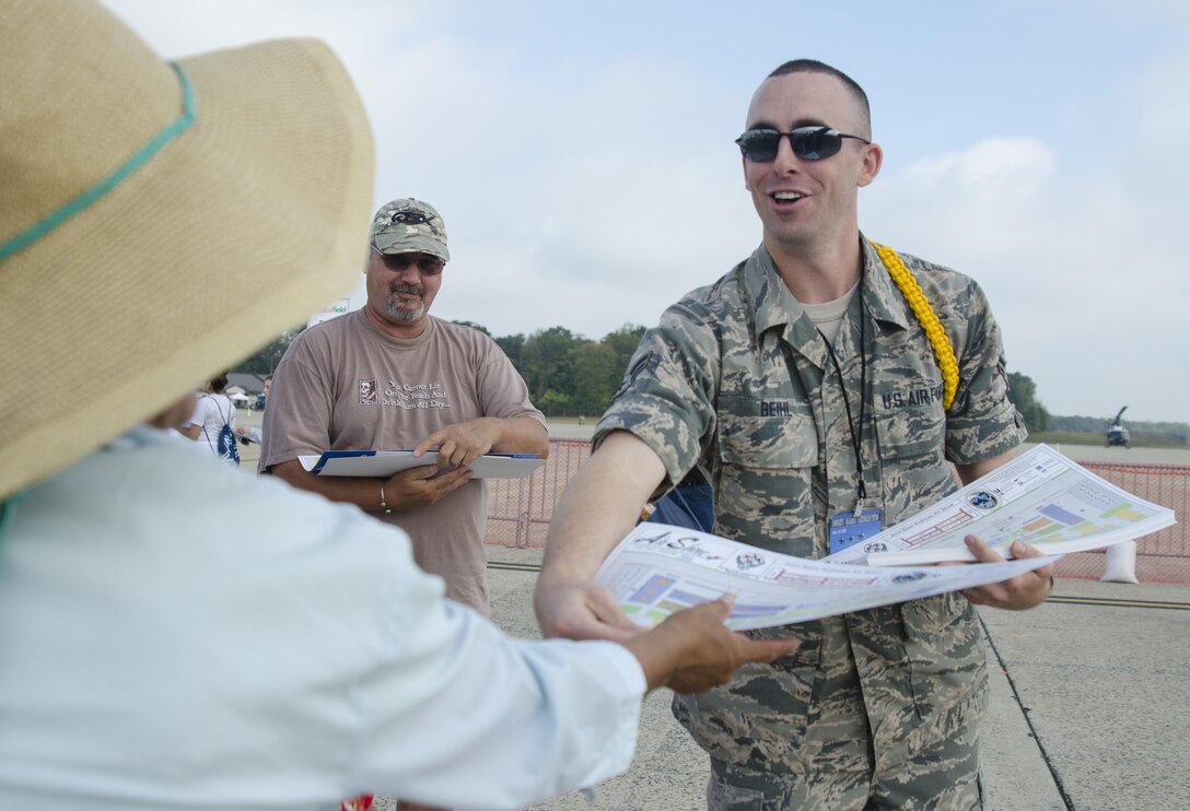 Air Force Airman 1st Class Travis Biehl hands a map to a visitor of the 2015 Joint Base Andrews Air Show Sept. 19, 2015. Biehl is one of 20 Basic Photojournalist Course students from the Defense Information School who augmented members of the JB Andrews Public Affairs staff during the air show.