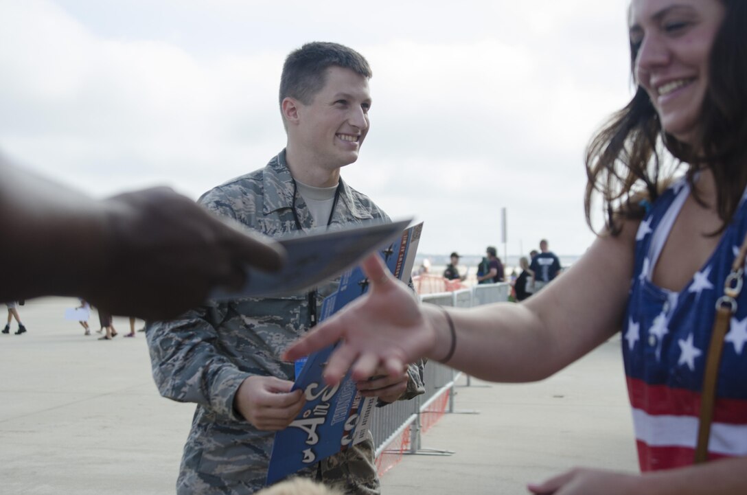 Air Force Airman 1st Class Keifer Bowes prepares to hand a map to visitors the 2015 Joint Base Andrews Air Show Sept. 19, 2015. Bowes is one of 20 Basic Photojournalist Course students from the Defense Information School who augmented members of the JB Andrews Public Affairs staff during the air show. The students facilitated civilian media access, aided visitors from the information booths and took photos of visitors and air show performances. (U.S. Air Force photo by Staff Sgt. David W. Carbajal/Released)