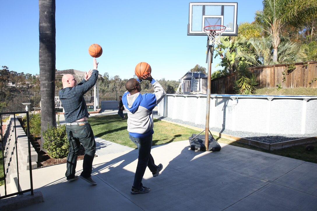 Lance Cpl. Miles Kalambokidis, left, a training clerk with Marine Wing Support Squadron 373 and a Glenwood, Iowa native, and Cpl. Willie Williams, right, an administrative clerk with Marine Aircraft Logistics Squadron 11 and a Richmond, Va. native, plays basketball at a San Diego family’s home Dec. 25. Employees at the Great Escape aboard Marine Corps Air Station Miramar, Calif. hosted the “Home for the Holidays” program and pairs single Marines and Sailors with families on Dec. 24 and 25. (U.S. Marine Corps photo by Sgt. Lillian Stephens/Released)