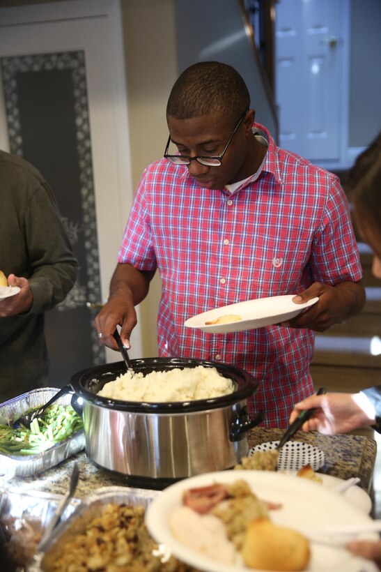 Cpl. Willie Williams, left, an administrative clerk with Marine Aircraft Logistics Squadron 11 and a Richmond, Va. native, prepares a plate of food during a family gathering in San Diego, Dec. 25. Williams participated in the Great Escape’s “Home for the Holidays” program, which paired single Marines and Sailors to accommodating families during the holiday season. (U.S. Marine Corps photo by Sgt. Lillian Stephens/Released)