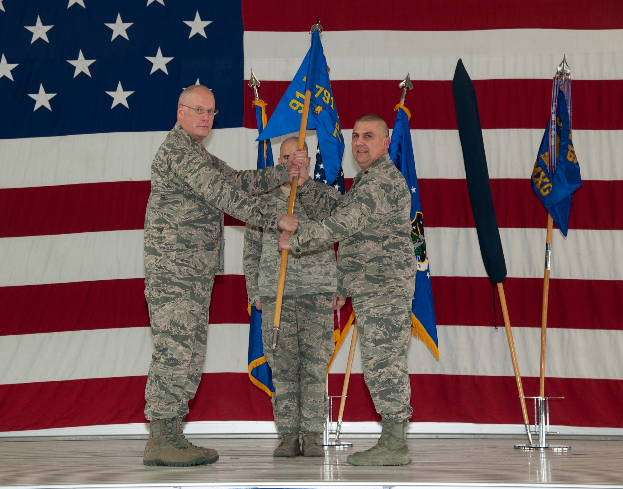Col. Earl Bennett, 91st Maintenance Group commander, hands the new 791st Maintenance Squadron guidon to Major Louis Rognoni, 791st MXS commander, at Minot Air Force Base, N.D., Jan. 4, 2015. During the ceremony the 91st Maintenance Operations Squadron was deactivated and the 791st MXS was activated. (U.S. Air Force photo/Airman 1st Class Christian Sullivan)