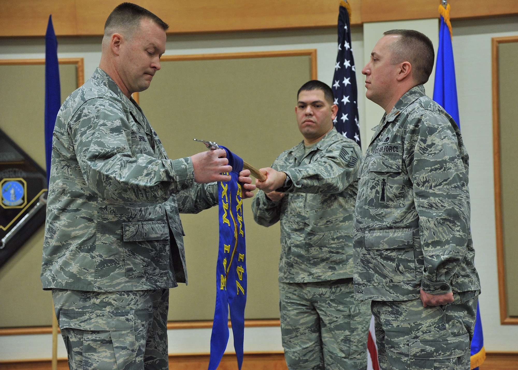 Col. Kenneth Speidel, 341st Maintenance Group commander, left, unfurls the 741st Maintenance Squadron guidon Dec. 30, 2015, formally signifying the squadron’s activation at Malmstrom Air Force Base, Mont., before Maj. James Spoo, 741st MXS commander, right, formally assumes command of the squadron. Guidon bearer Master Sgt. Daniel Olivares, 741st MXS first sergeant, center, looks on. The Air Force inactivated the 341st Maintenance Operations Squadron at Malmstrom Sept. 30, 2015, to redesignate it as the 741st MXS and standardize all maintenance organizations across the force. (U.S. Air Force photo/John Turner)