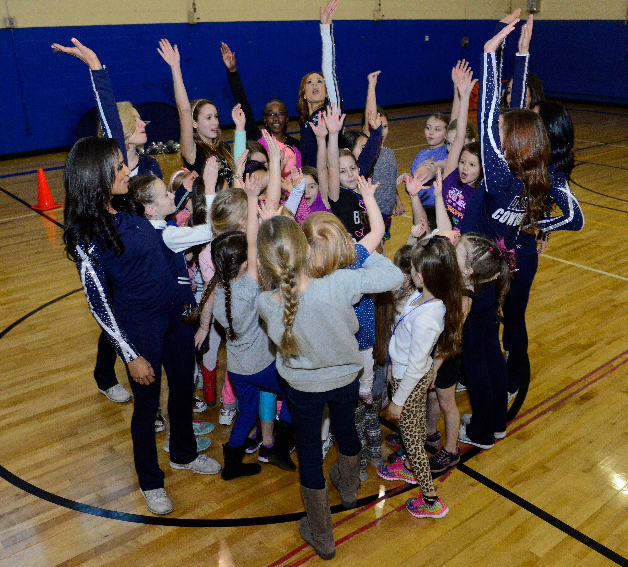 Military children and members of the Dallas Cowboys Cheerleaders celebrate after a cheer clinic in the Osan Youth Center during the 74th annual United Service Organizations tour on Osan Air Base, Republic of Korea, Dec. 25, 2015. The cheerleaders toured Air Force and Army installations across the peninsula. Many cheerleaders on tour were stationed throughout Korea as children and shared childhood stories during the clinics. (U.S. Air Force photo/Senior Airman Kristin High)