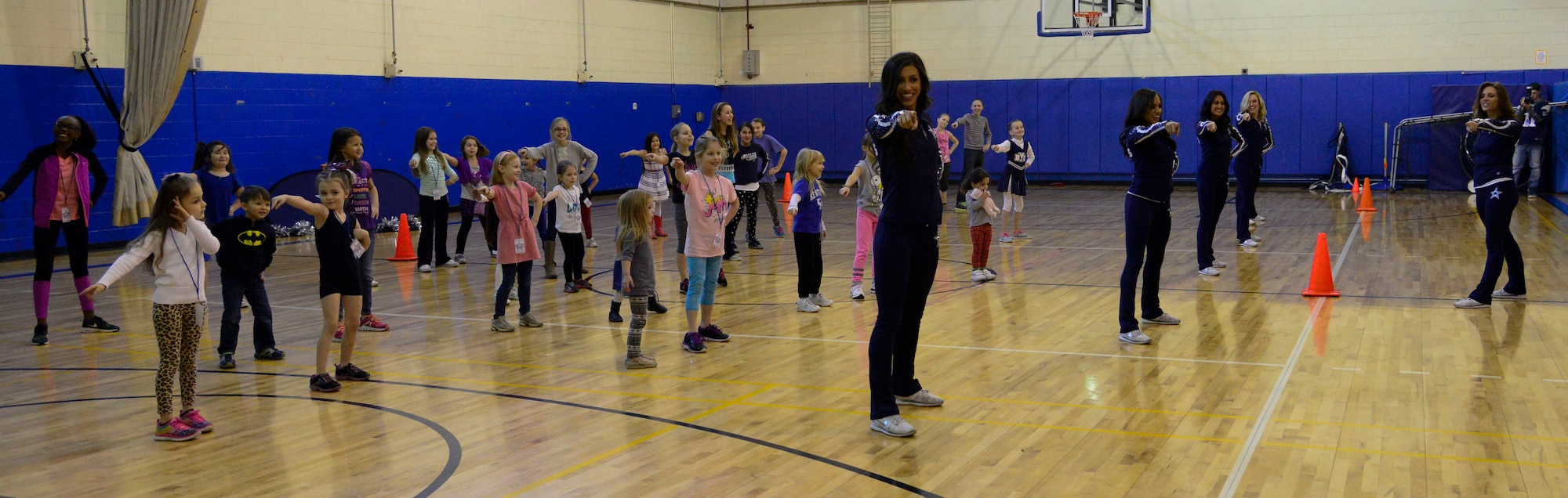 Members of the Dallas Cowboys Cheerleaders practice a dance routine with military children during the 74th annual United Service Organizations tour on Osan Air Base, Republic of Korea, Dec. 25, 2015. The cheerleaders provided cheer clinics for military children throughout their tour teaching in the ROK, proper stretches and basic dance moves to a choreographed routine. (U.S. Air Force photo/Senior Airman Kristin High)