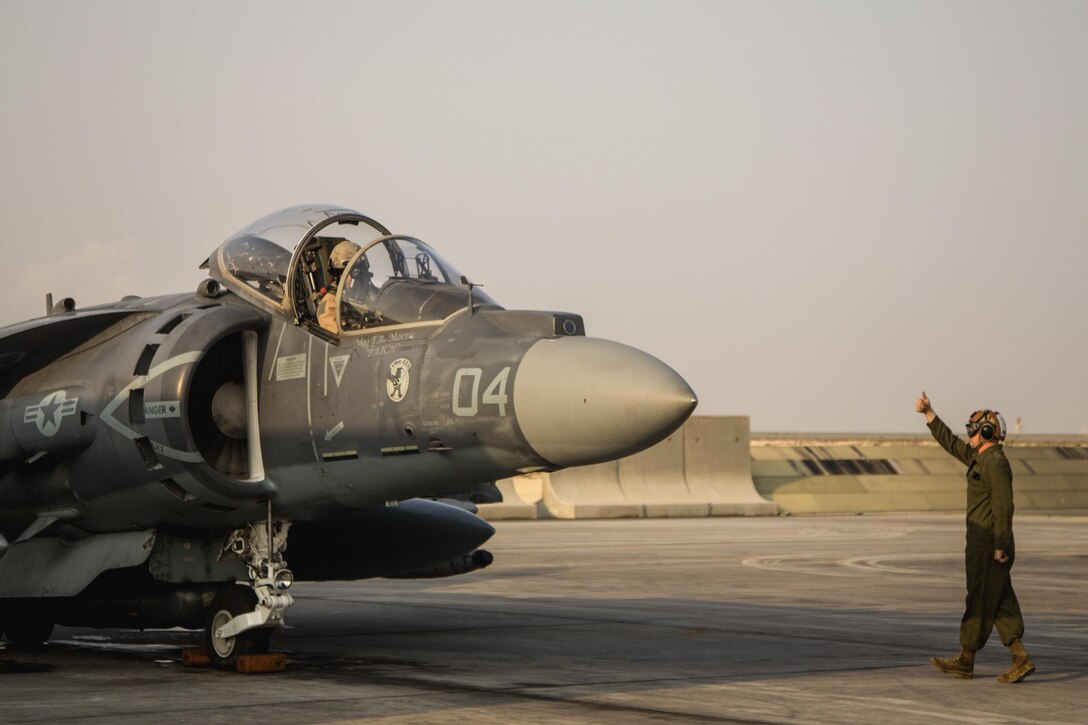 A U.S. Marine gives the thumbs up to a pilot after performing preflight checklists on an AV-8B Harrier on Isa Air Base, Bahrain, Dec. 31, 2015. U.S. Marine Corps photo by Cpl. Akeel Austin