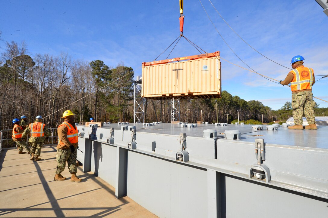 Sailors from Navy Cargo Handling Battalion 1 lower a shipping container onto a hatch cover of a Navy Expeditionary Logistics Support Group land ship during refresher training in support of Operation Deep Freeze 2016 in Williamsburg, Va., Jan. 6, 2016. Fifty-four active and reserve component sailors were training in preparation for departure to McMurdo Station, Antarctica, in support of the National Science Foundation. U.S. Navy photo by Chief Petty Officer Edward Kessler