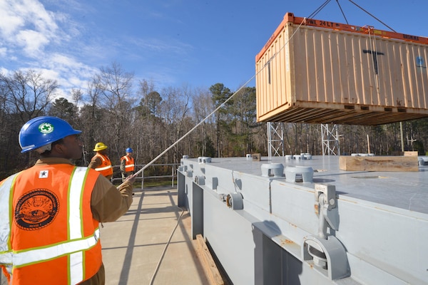 Sailors from Navy Cargo Handling Battalion 1 lower the last shipping container onto a hatch cover of a Navy Expeditionary Logistics Support Group land ship during refresher training in support of Operation Deep Freeze 2016 in Williamsburg, Va., Jan. 6, 2016. Fifty-four active and reserve component sailors were training in preparation for departure to McMurdo Station, Antarctica, in support of the National Science Foundation. U.S. Navy photo by Chief Petty Officer Edward Kessler