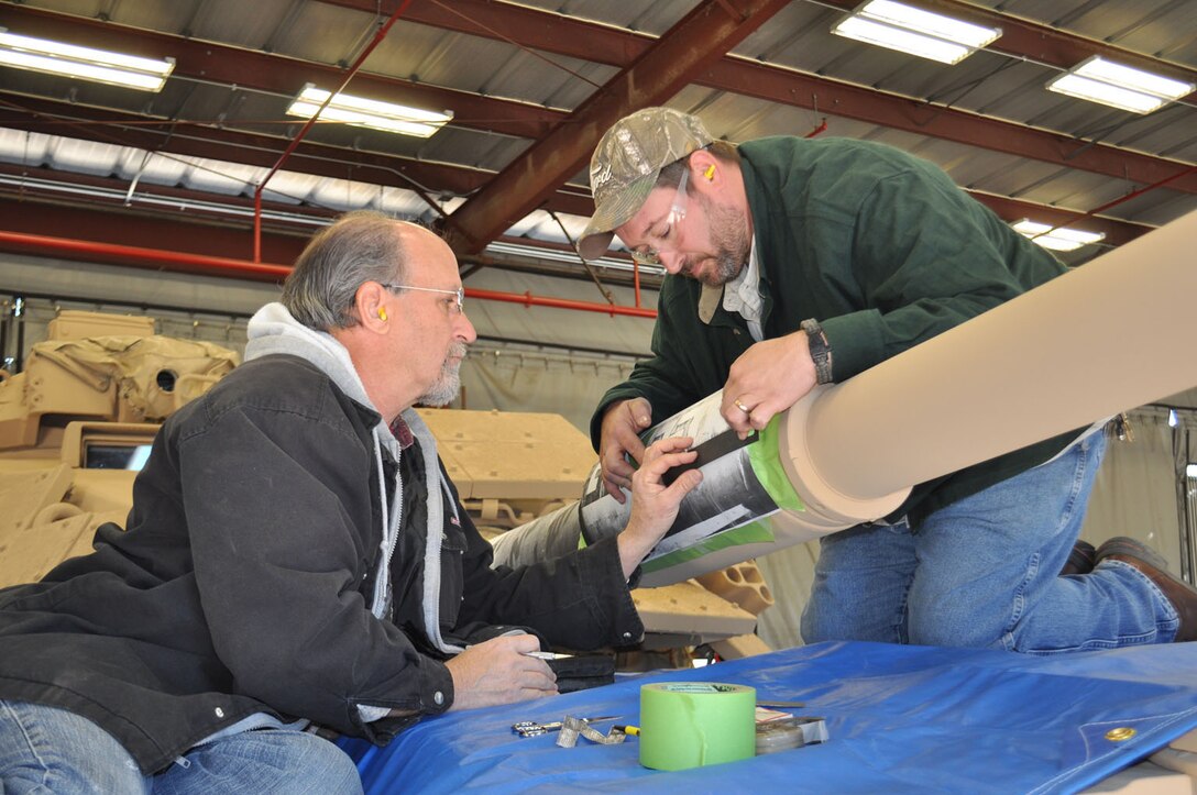 Marine Depot Maintenance Command artisans stencil the gun barrel of the Genesis II, an M60A1 Main Battle Tank, as part of the final steps in a restoration project between MDMC and National Museum of the Marine Corps, Dec. 15, 2015.