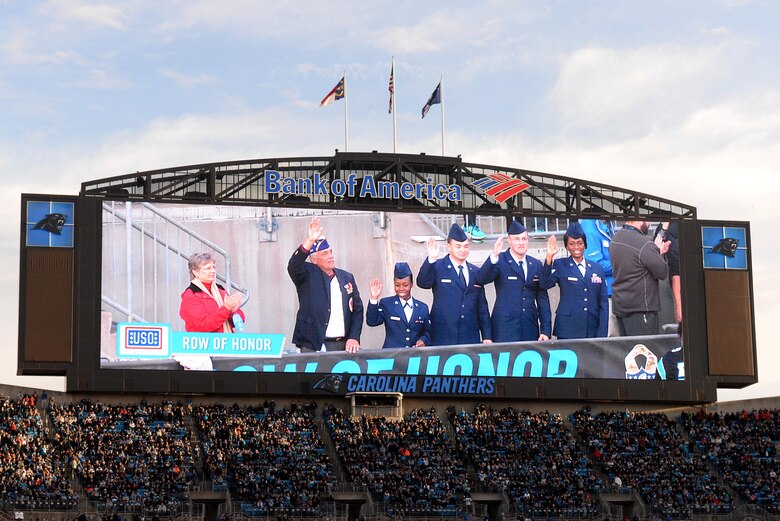 Military service members sitting in the stadium’s USO of North Carolina Row of Honor wave to all those watching the Panthers vs. Buccaneers game, Jan. 3, 2016, at Bank of America Stadium in Charlotte, North Carolina. The service members were randomly selected to receive free seats to the football game to pay tribute to their service. (U.S. Air Force photo/Airman 1st Class Ashley Williamson)