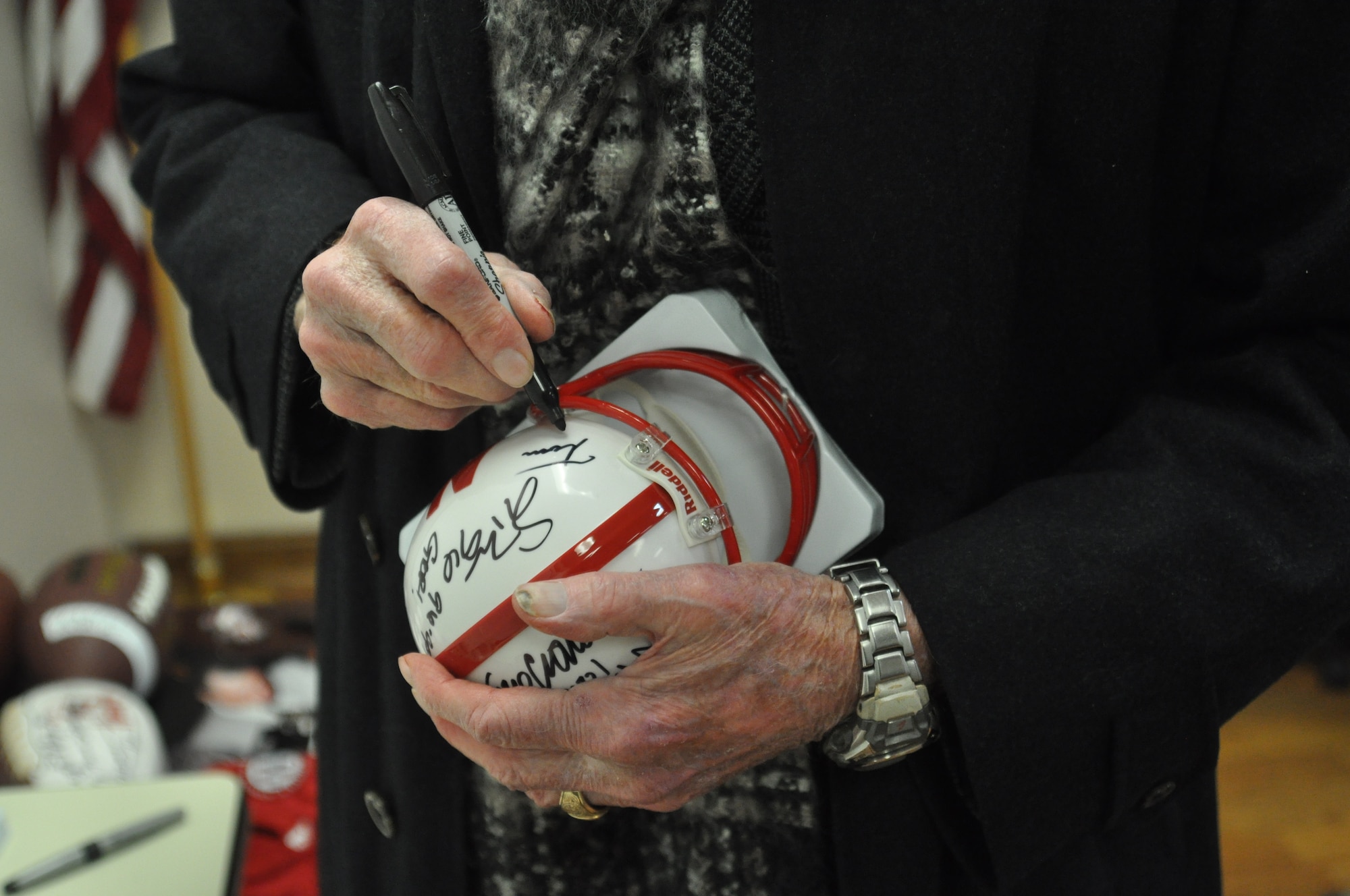 Retired Nebraska Cornhuskers coach, Tom Osborne, signs a mini- football helmet in the in the Bennie Davis Maintenance Facility, Offutt Air Force Base, Neb., Jan. 5. Osborne went on to speak to hundreds of Team Offutt Airmen about the importance of integrity. (U.S. Air Force photo by Senior Airman Rachel Hammes)