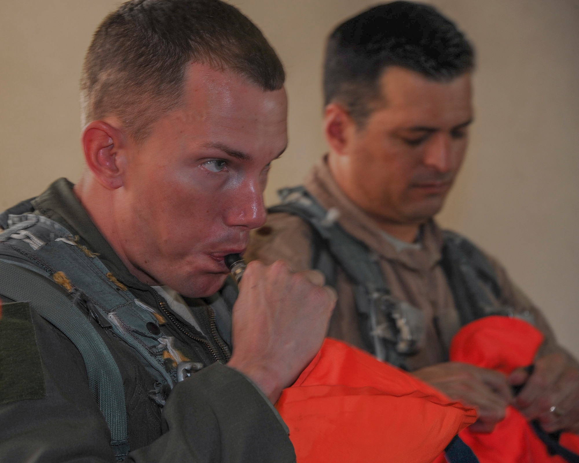 U.S. Air Force Staff Sgt. Corey Cody, 43rd Electronic Combat Squadron flight engineer, and Lt. Col. Lance Benson, 43th ECS commander, manually inflate life preservers during Survival, Evasion, Resistance, Escape training refresher at Davis-Monthan Air Force Base, Ariz., Jan. 6, 2016. The personal life preservers aid in keeping the flight crew floating even while wearing flight gear. (U.S. Air Force photo by Airmen 1st Class Ashley N. Steffen/Released)  