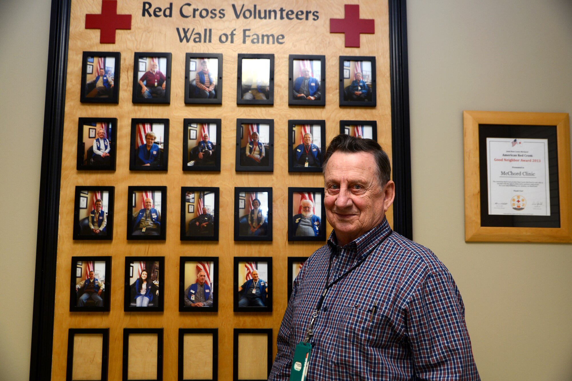Chief Master Sgt. (retired) Bob Jeffrey, McChord Clinic Red Cross coordinator, stands in front of the ‘Red Cross Volunteers Wall of Fame’ by the McChord Field pharmacy will call at Joint Base Lewis McChord, Dec. 29, 2015. Jeffrey has been the Red Cross Coordinator at the clinic for the last 15 years and oversees 31 Red Cross volunteers at McChord Field. (Air Force photo/Senior Airman Naomi Shipley)