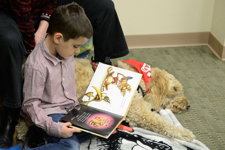James Vandervoort, 6, reads to Swivelshot, a goldendoodle therapy dog, at the Paws to Read program at the Joint Base Elmendorf-Richardson Library, Dec. 19, 2015. Paws to read is a program where children who have difficulty reading are able to read to service dogs. James is the son of Edward and Mollie Vandervoort. (U.S. Air Force photo by Airman Valerie Monroy)