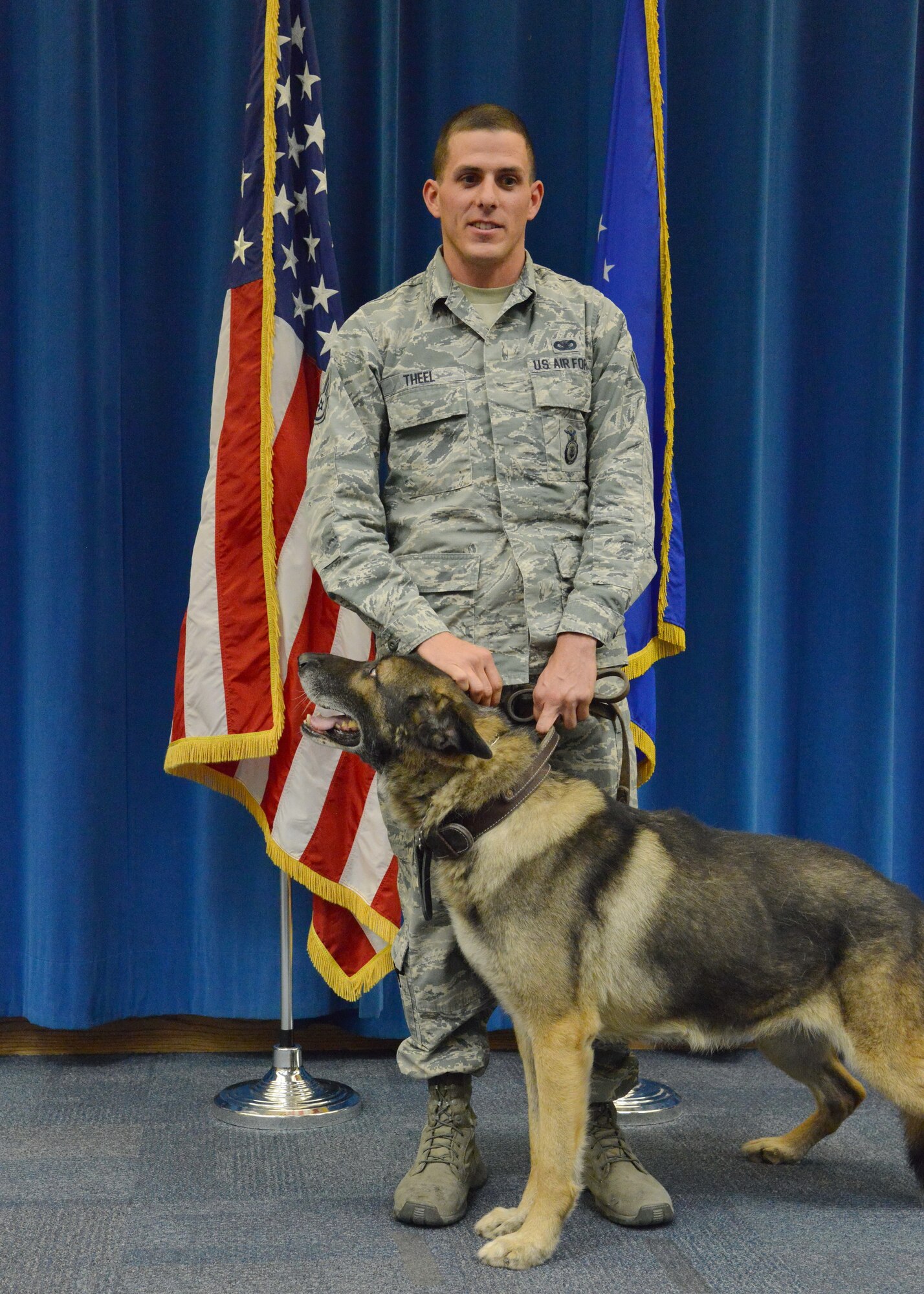 Capa, a 7-year-old German shepherd, stands with her handler Staff Sgt. Tanner Theel, 377th Security Forces Squadron, at a retirement ceremony Dec. 16. Capa was retired after working in the Air Force for five years, specializing in drug searching. The canine deployed to Kandahar, Afghanistan, where he spent more than 700 hours on outside the wire missions and searched thousands of pieces of luggage. (Photo by Jamie Burnett)
