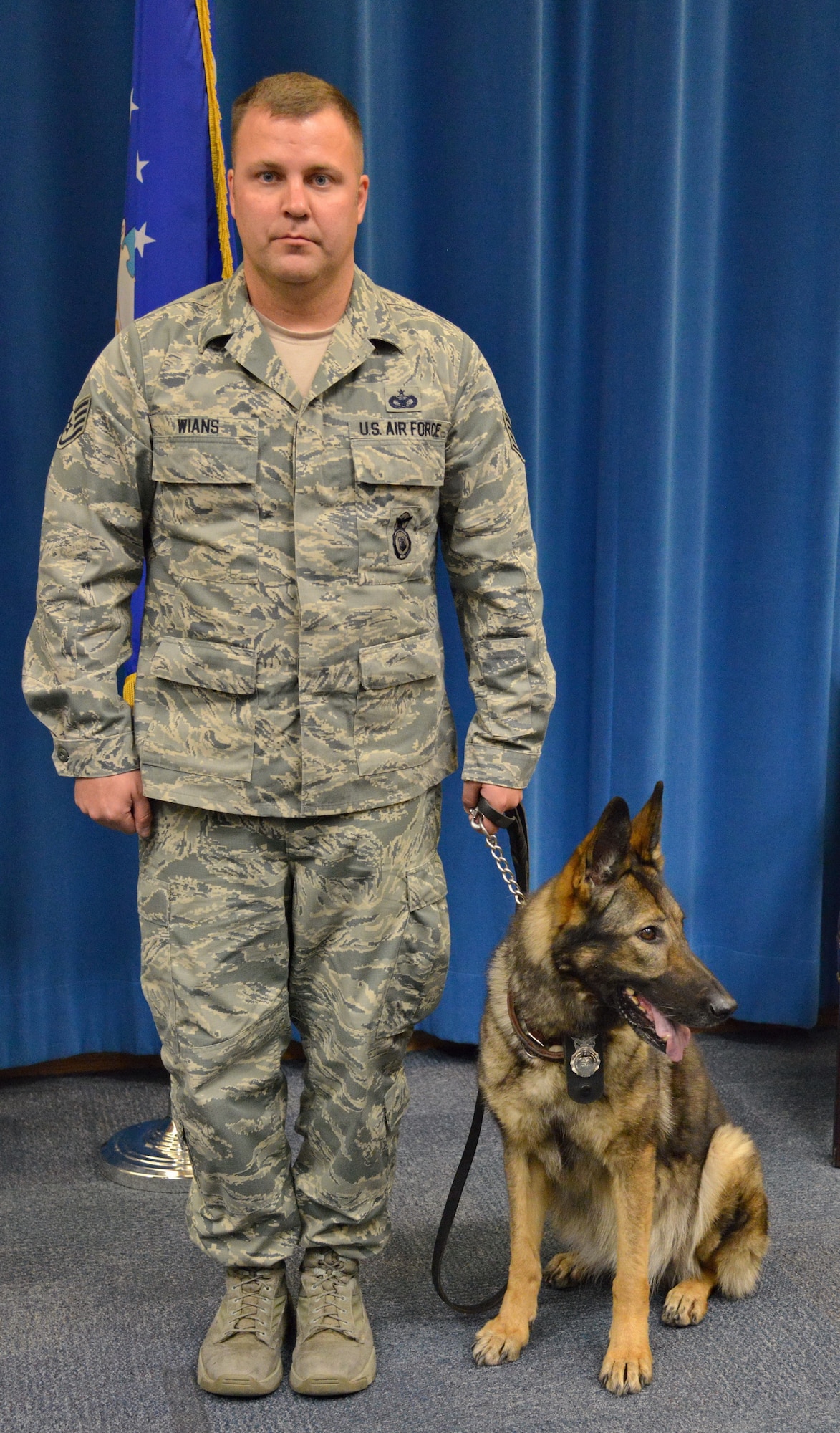 Alea, a 10-year-old German shepherd, stands with her handler Staff Sgt. Richard Wians, 377th Security Forces Squadron, at a retirement ceremony Dec. 16. Alea was retired after working in the Air Force for eight years. The canine took part in more than 30 combat missions in Afghanistan, where she uncovered four heroin labs and $7 million of illegal narcotics.  (Photo by Jamie Burnett)