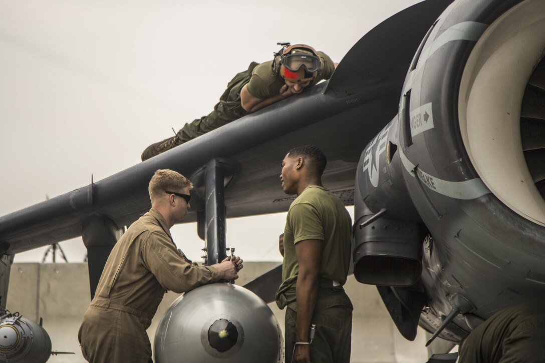 U.S. Marines talk as they perform corrective and preventative maintenance on an AV-8B Harrier on Isa Air Base, Bahrain, Dec. 31, 2015. U.S. Marine Corps photo by Cpl. Akeel Austin 