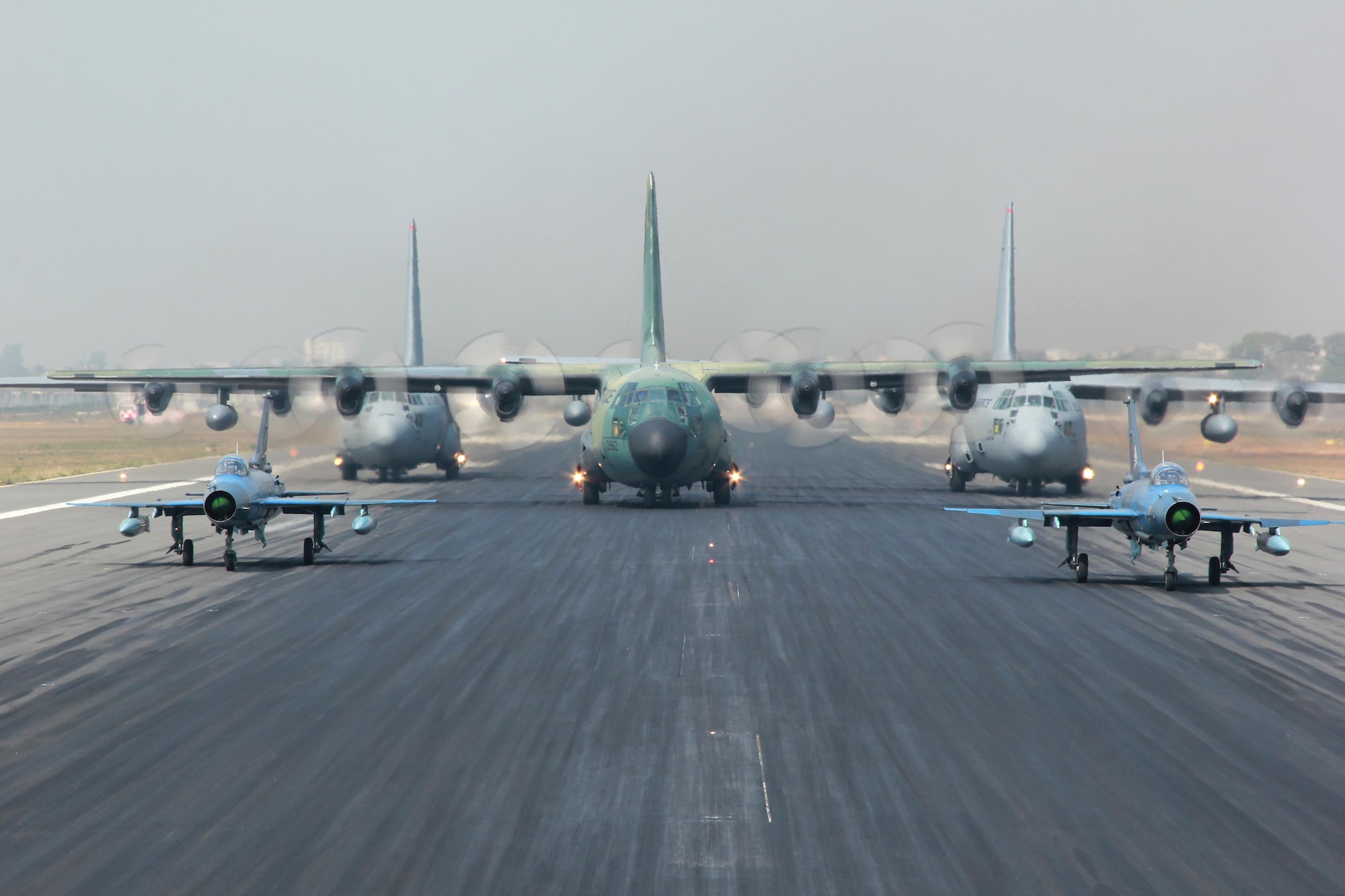Two Bangladesh air force (BAF) F-7BG Defenders, a BAF C-130B Hercules, and two U.S. Air Force C-130H Hercules aircraft prepare to take off Jan. 28, 2015, from BAF Base Bangabandhu, Bangladesh, during exercise Cope South. Cope South is a Pacific Air Forces-sponsored, bilateral tactical airlift exercise conducted in Bangladesh, with a focus on cooperative flight operations, day and night low-level navigation, tactical airdrop, and air-land missions as well as subject matter expert exchanges in the fields of operations, maintenance and rigging disciplines. The C-130H is assigned to the 374th Airlift Wing at Yokota Air Base, Japan. (Courtesy photo/Bangladesh air force)