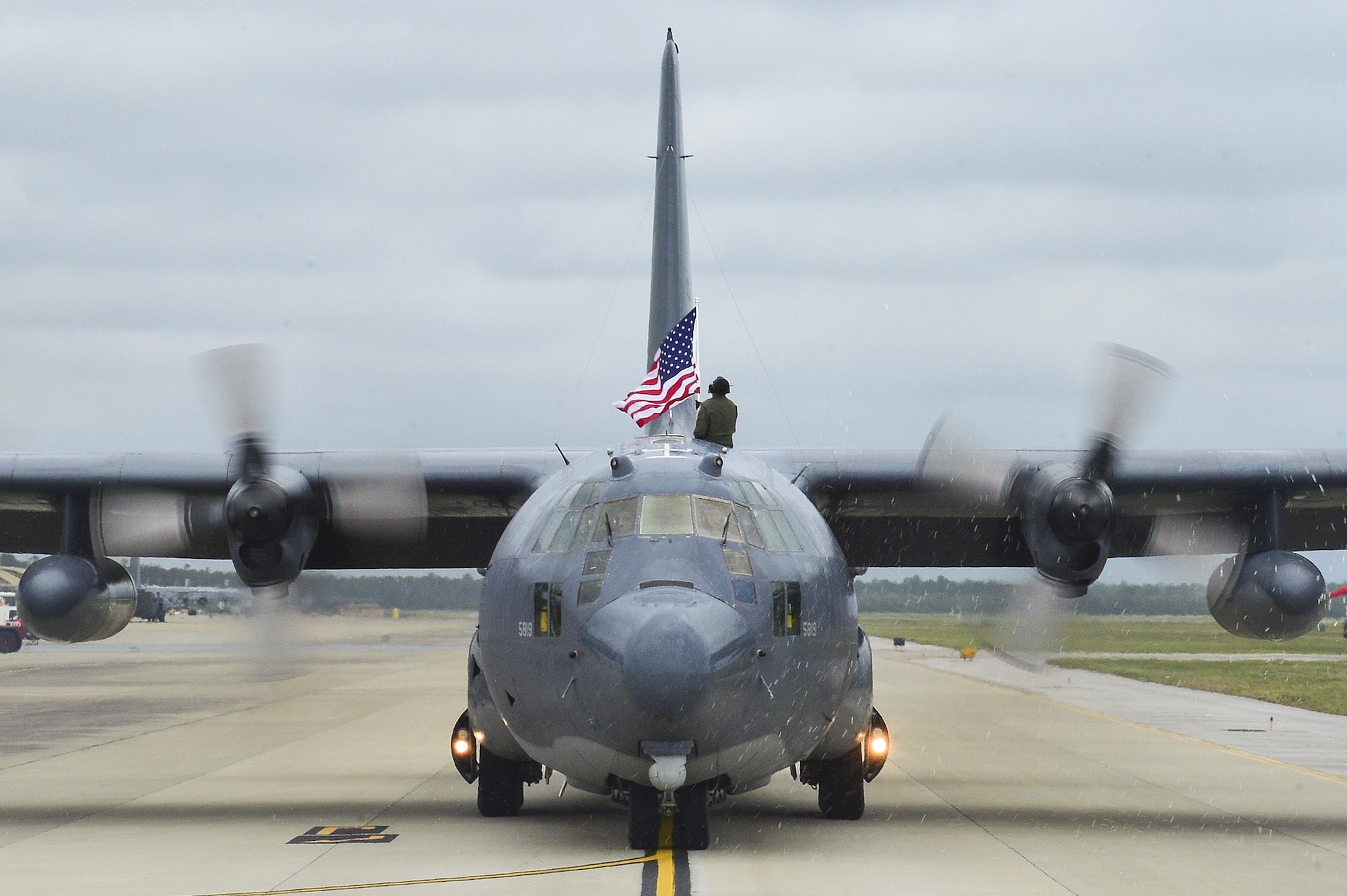 Tech. Sgt. Bruce Ramos, a Detachment 1, 1st Special Operations Group radio operator, raises an American flag from an MC-130P Combat Shadow while it taxies at Hurlburt Field, Fla., May 15, 2015. The final two MC-130Ps in the Air Force landed for the last time at Hurlburt Field in front of more than 400 people, and their last flight was to the boneyard at Davis-Monthan Air Force Base, Ariz., June 1, 2015. (U.S. Air Force photo/Senior Airman Jeff Parkinson)