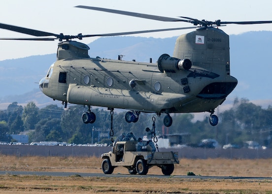 Airmen from the 60th Aerial Port Squadron and members of the Army National Guard's 49th Police Brigade practice loading and sling loading vehicles on a CH-47 Chinook Oct. 14, 2015, at Travis Air Force Base, Calif. The units also practiced nighttime operations with the aid of night vision goggles. (U.S. Air Force photo/T.C. Perkins Jr.)