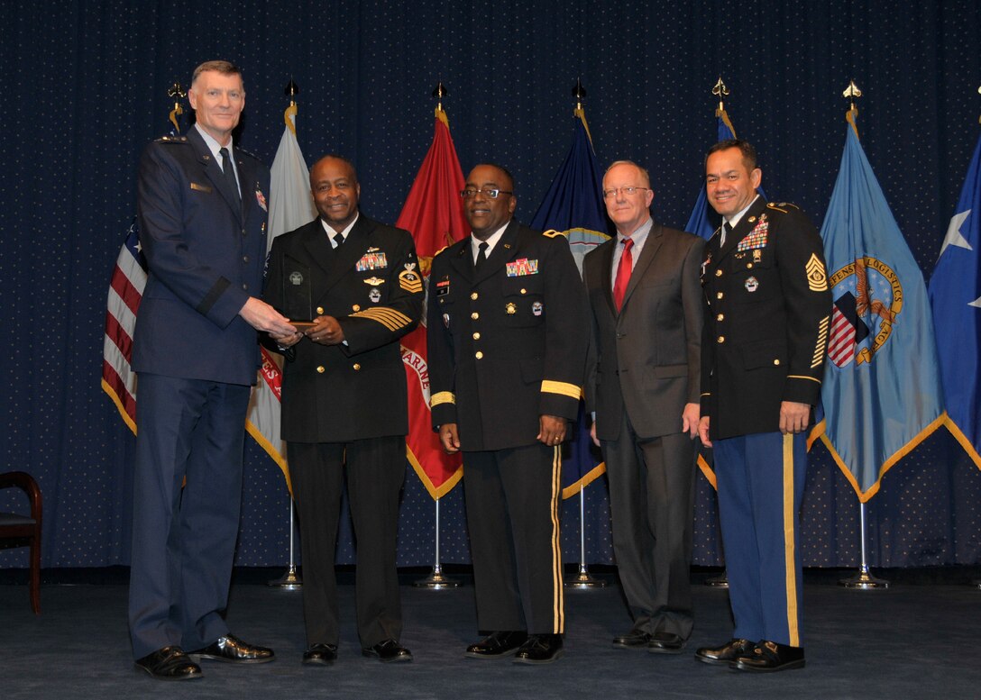 DLA director Air Force Lt. Gen. Andy Busch, left, recognizes DLA Distribution Operation Team Atlanta team member Navy Senior Chief Logistics Specialist Vascoe Rozier III as the Agency’s Joint Reserve Force Senior Enlisted Member of the Year at the 48th annual employee recognition ceremony Dec. 10. Distribution’s commander Army Brig. Gen. Richard Dix, third from right, Robert McCullough, DLA J9 deputy director and DLA Senior Enlisted Leader Army Command Sgt. Maj. Charles Tobin, far right, were also on-hand to present the award. 