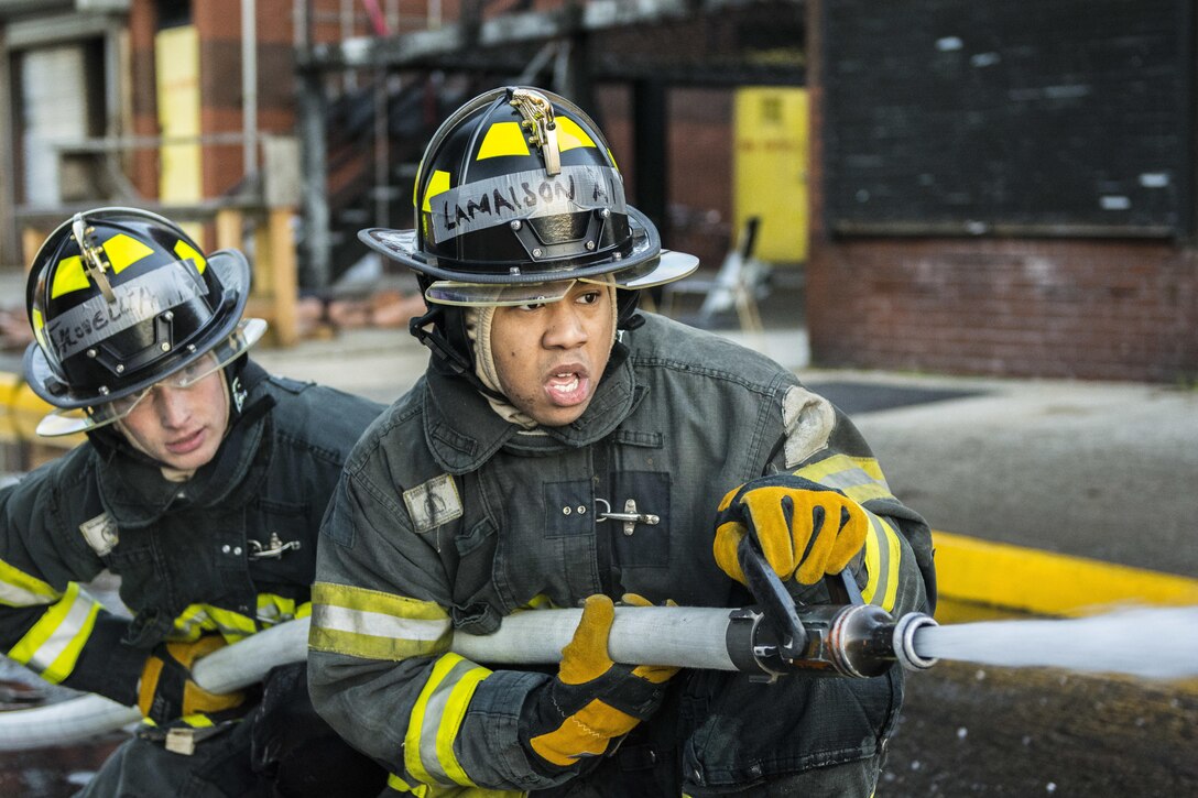 Probationary firefighters in their second week of training at the New York City Fire Academy on Russell Island in New York City, perform a drill known as motivation alley in which pairs of two firefighters must travel 100 feet down a road from a kneeling position carrying a charged 1¾-inch fire hose to put out a mock flame, Jan. 6, 2016. Drill sergeant leaders from the United States Army Drill Sergeant Academy on Fort Jackson, S.C., were at the Fire Academy Jan. 4-8, to observe training as part of a collaboration between the Fire Department of New York and the Center for Initial Military Training providing lessons learned and offering alternate training methods for new recruits. (U.S. Army photo by Sgt. 1st Class Brian Hamilton)