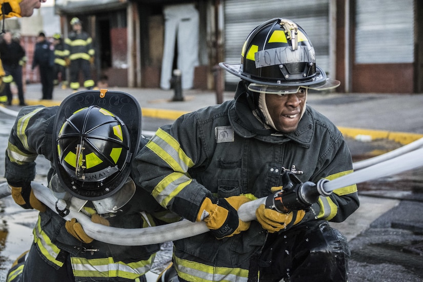 Probationary firefighters in their second week of training at the New York City Fire Academy on Russell Island in New York City, perform a drill known as motivation alley in which pairs of two firefighters must travel 100 feet down a road from a kneeling position carrying a charged 1¾-inch fire hose to put out a mock flame, Jan. 6, 2016. Drill sergeant leaders from the United States Army Drill Sergeant Academy on Fort Jackson, S.C., were at the Fire Academy Jan. 4-8, to observe training as part of a collaboration between the Fire Department of New York and the Center for Initial Military Training providing lessons learned and offering alternate training methods for new recruits. (U.S. Army photo by Sgt. 1st Class Brian Hamilton)