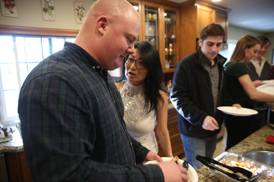 Lance Cpl. Miles Kalambokidis, left, a training clerk with Marine Wing Support Squadron 373 and a Glenwood, Iowa, native, joins the family gathering of Lisa Lindgren, right, a participant in the "Home for the Holidays" program and a San Diego native, for a family dinner in Dec. 25. Kalambokidis participated in the Great Escape’s “Home for the Holidays” program, which paired single Marines and Sailors to accommodating families during the holiday season. (U.S. Marine Corps photo by Sgt. Lillian Stephens/Released)