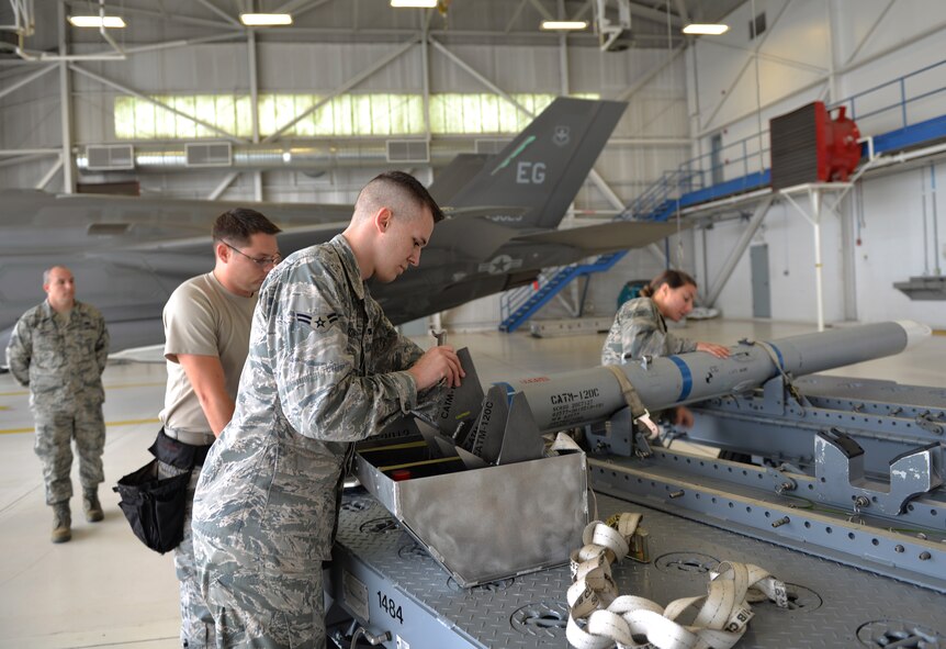 Airmen 1st Class Robert Honeycutt, 33rd Aircraft Maintenance Squadron weapons load crew member, and team members inspects the fins and wings of an Air Intercept Missile 120 during a load competition at Eglin Air Force Base, Fla., Jan. 8, 2016. During this event teams are evaluated on the level of safety, efficiency and speed displayed while loading munitions.  (U.S. Air Force Photo/Senior Airman Andrea Posey)