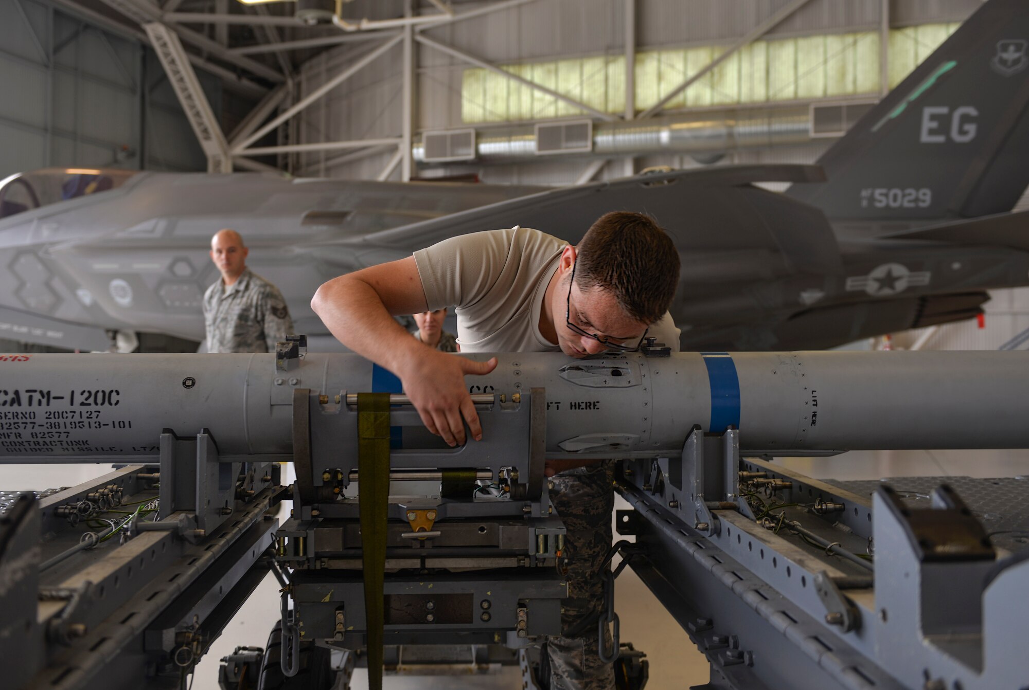 Staff Sgt. Mark Mahacsi, 33rd Aircraft Maintenance Squadron weapons load crew team chief, secures an Air Intercept Missile 120 to a lift truck during a load competition at Eglin Air Force Base, Fla., Jan. 8, 2016. Load teams work together to load munitions into an F-35A Lightning II as they are timed and inspected. (U.S. Air Force Photo/Senior Airman Andrea Posey)