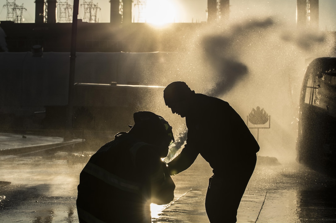 Capt. Matthew Cregin, an instructor with the New York City Fire Academy, assists probationary firefighters in their second week of training at the school on Russell Island in New York City, Jan. 6, 2015. The new firefighters are performing a drill known as motivation alley in which pairs of two firefighters must travel 100 feet down a road from a kneeling position carrying a charged 1¾-inch fire hose to put out a mock flame. Drill sergeant leaders from the United States Army Drill Sergeant Academy on Fort Jackson, S.C. were at the Fire Academy Jan. 4-8, to observe training as part of a collaboration between the Fire Department of New York and the Center for Initial Military Training providing lessons learned and offering alternate training methods for new recruits. (U.S. Army photo by Sgt. 1st Class Brian Hamilton)