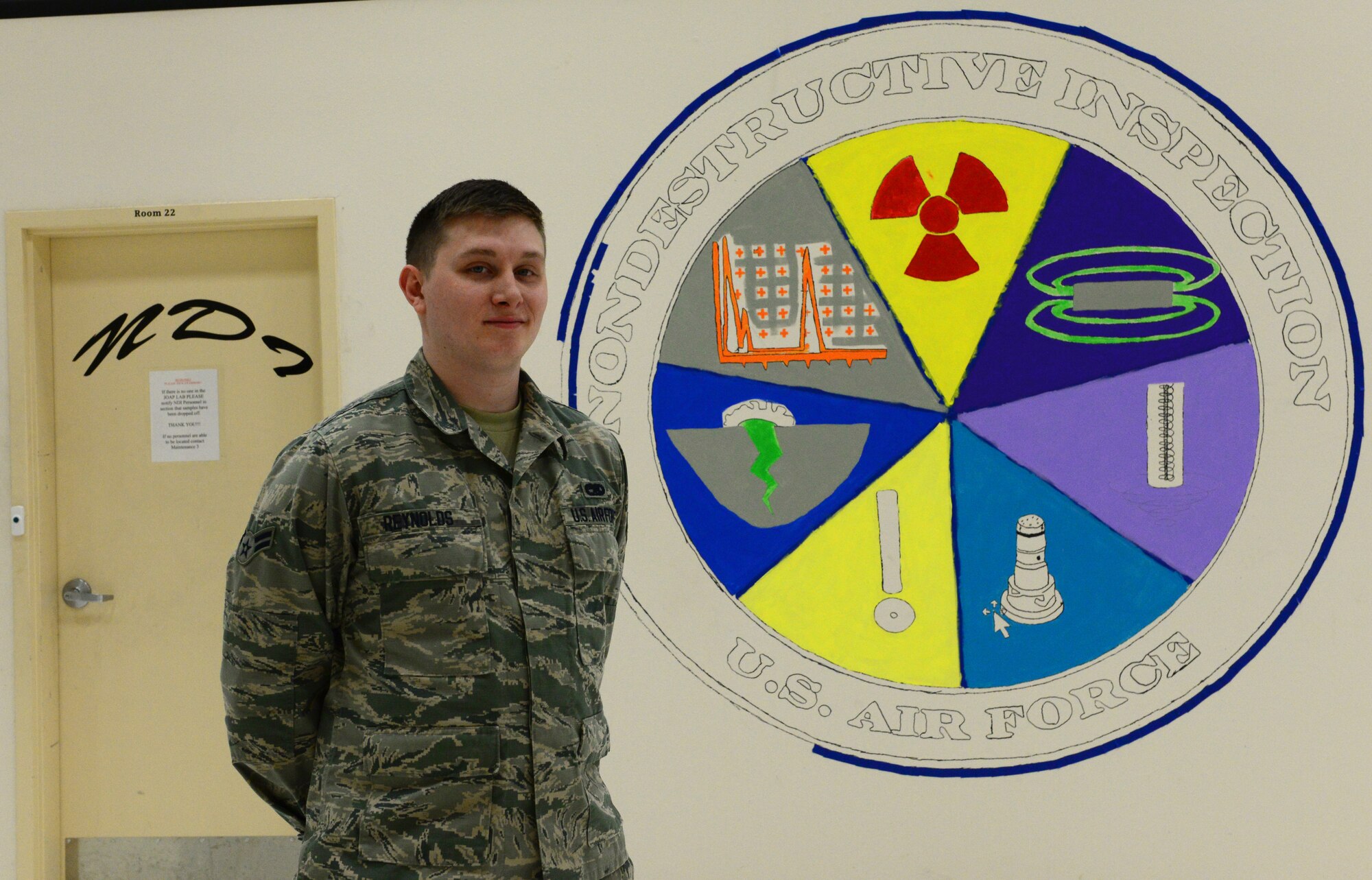 U.S. Air Force Airman 1st Class Christopher Reynolds Jr., a 354th Maintenance Squadron nondestructive inspection journeyman, takes a short break Jan. 6, 2016, at Eielson Air Force Base, Alaska. Reynolds took initiative to draw the emblem of his career field on their shop wall and is in the process of completing the painting. (U.S. Air Force photo by Airman 1st Class Cassandra Whitman/Released)