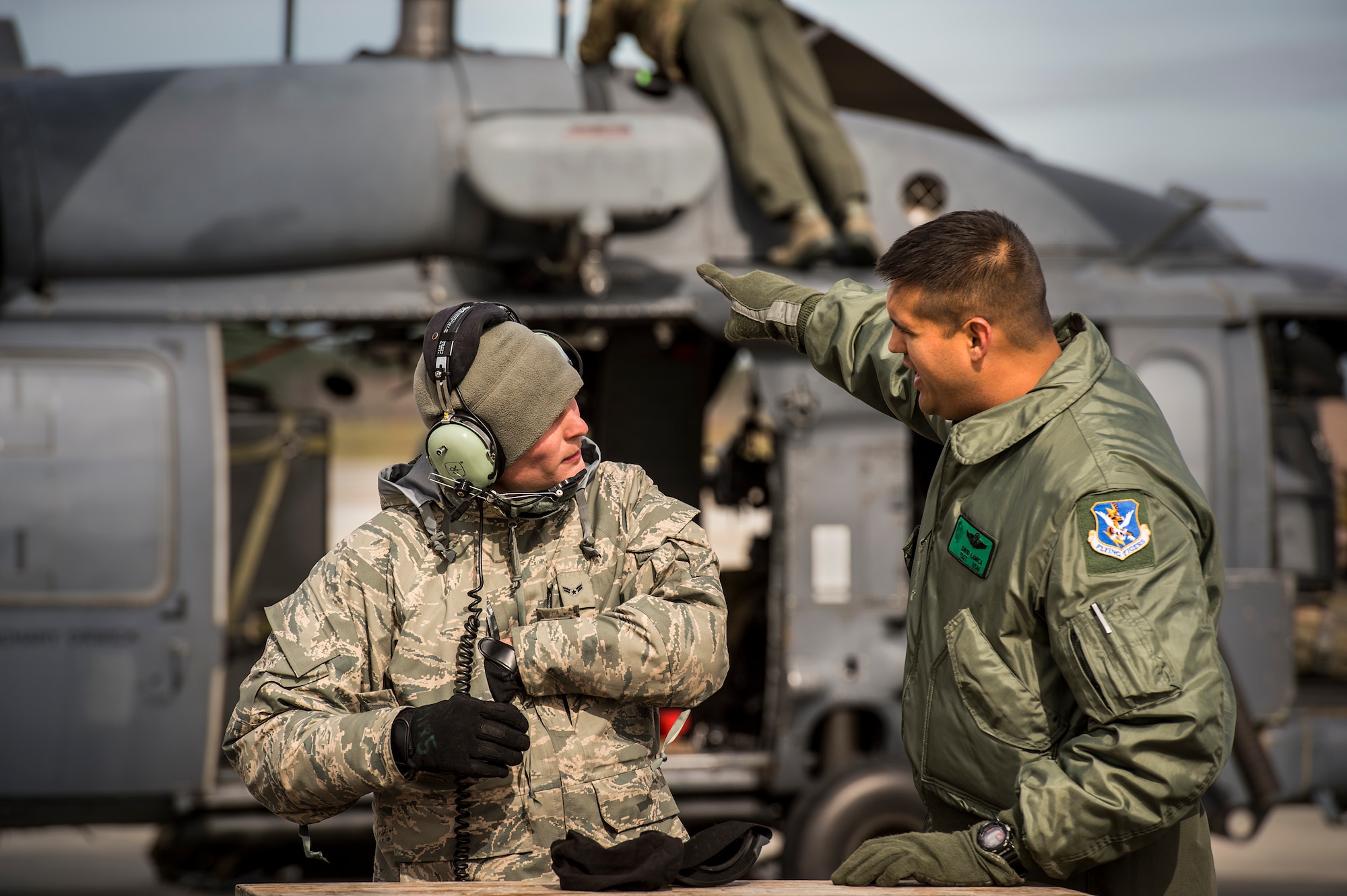 U.S. Air Force Tech. Sgt. David Luca, right, 41st Rescue Squadron special missions aviator, points towards an HH-60G Pave Hawk while speaking to Airman 1st Class Alex Regan, 41st Helicopter Maintenance Unit crew chief, Jan. 6, 2016, at Moody Air Force Base, Ga. Aircrew members and maintenance personnel work together during pre-flight inspections in order to ensure aircraft are safe to fly. (U.S. Air Force photo by Senior Airman Ryan Callaghan/Released)