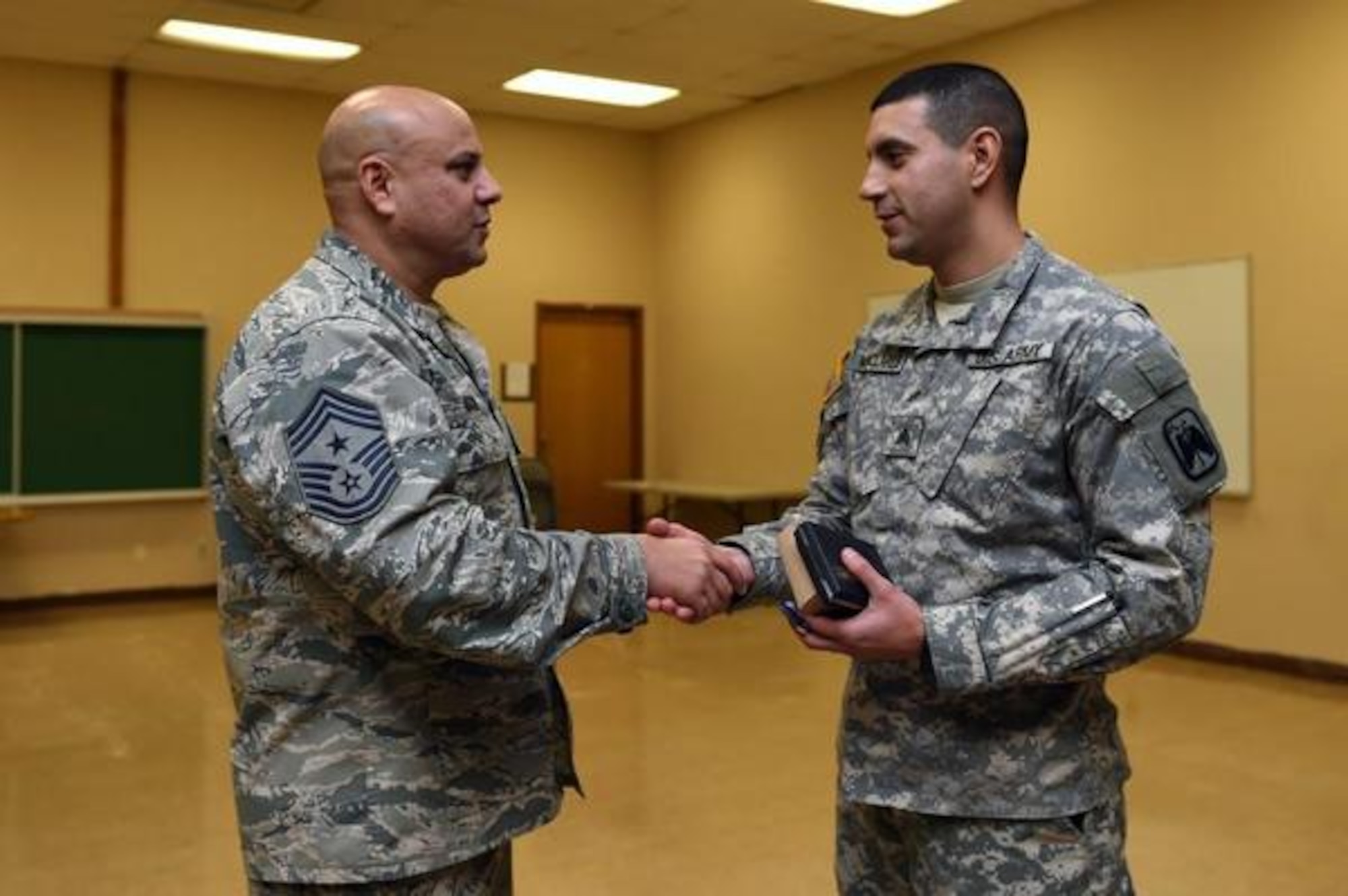Chief Master Sergeant Zaki J. Mazid, left, 62nd Airlift Wing command chief master sergeant, congratulates Sgt. Sergio A. Nanclares, 16th Combat Aviation Brigade, after Nanclares was presented the Air Force Achievement Medal for his efforts in translating for the Columbia president visiting Joint Base Lewis-McChord in November. (Courtesy photo)