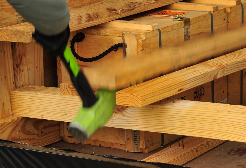 An 86th Munitions Squadron Airman breaks apart wood framing to release crates containing explosives Dec. 8, 2015, at Ramstein Air Base, Germany. Ramstein is the hub for shipping munitions to NATO partners. (U.S. Air Force photo/Airman 1st Class Larissa Greatwood)