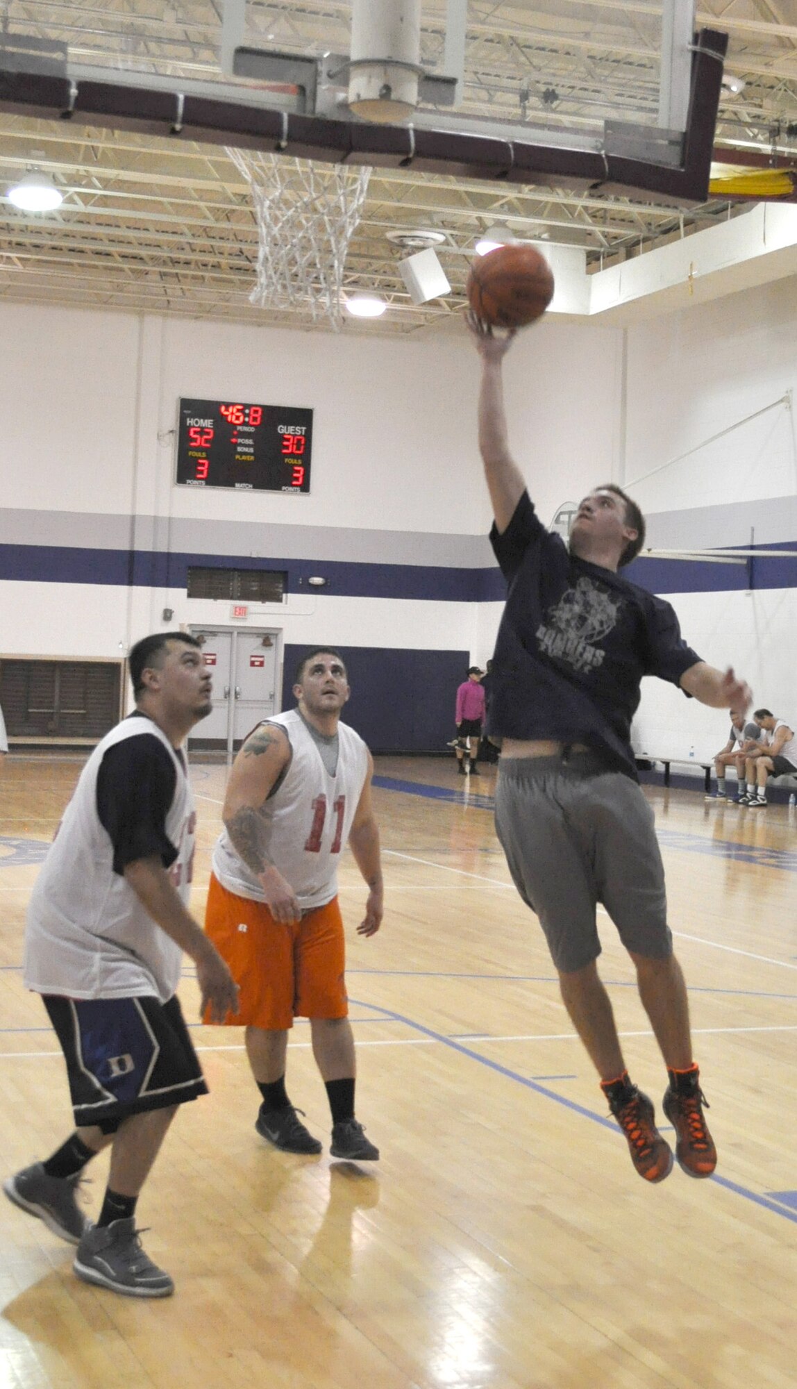 Bomber Ben Kelley leaps high with the ball late in the Dec. 16 game against 72 ABW (CE) as No. 11 Ray Green and No. 22 Michael Green look on. The Bombers prevailed 54-33. (Air Force photo by John Parker/Released)