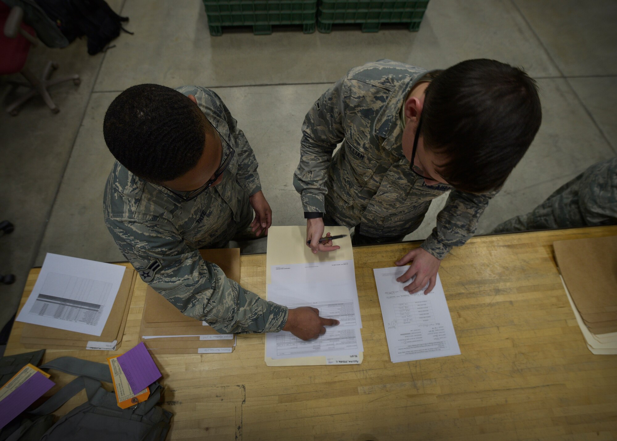U.S. Air Force Airman 1st Class Bakari Tate, left, an individual protective equipment apprentice with the 35th Logistics Readiness Squadron, issues out IPE to Airman Steven Pulliam, an installation entry controller with the 35th Security Forces Squadron, at Misawa Air Base, Japan, Jan. 6, 2016. IPE Airmen issue all in-processing active-duty members a training C-bag, consisting of a joint service lightweight integrated suit technology coat and trousers, flak vest, M50 gas mask, chemical boots, chemical gloves, glove inserts, web belt, canteen, helmet and suspenders. (U.S. Air Force photo by Senior Airman Deana Heitzman)