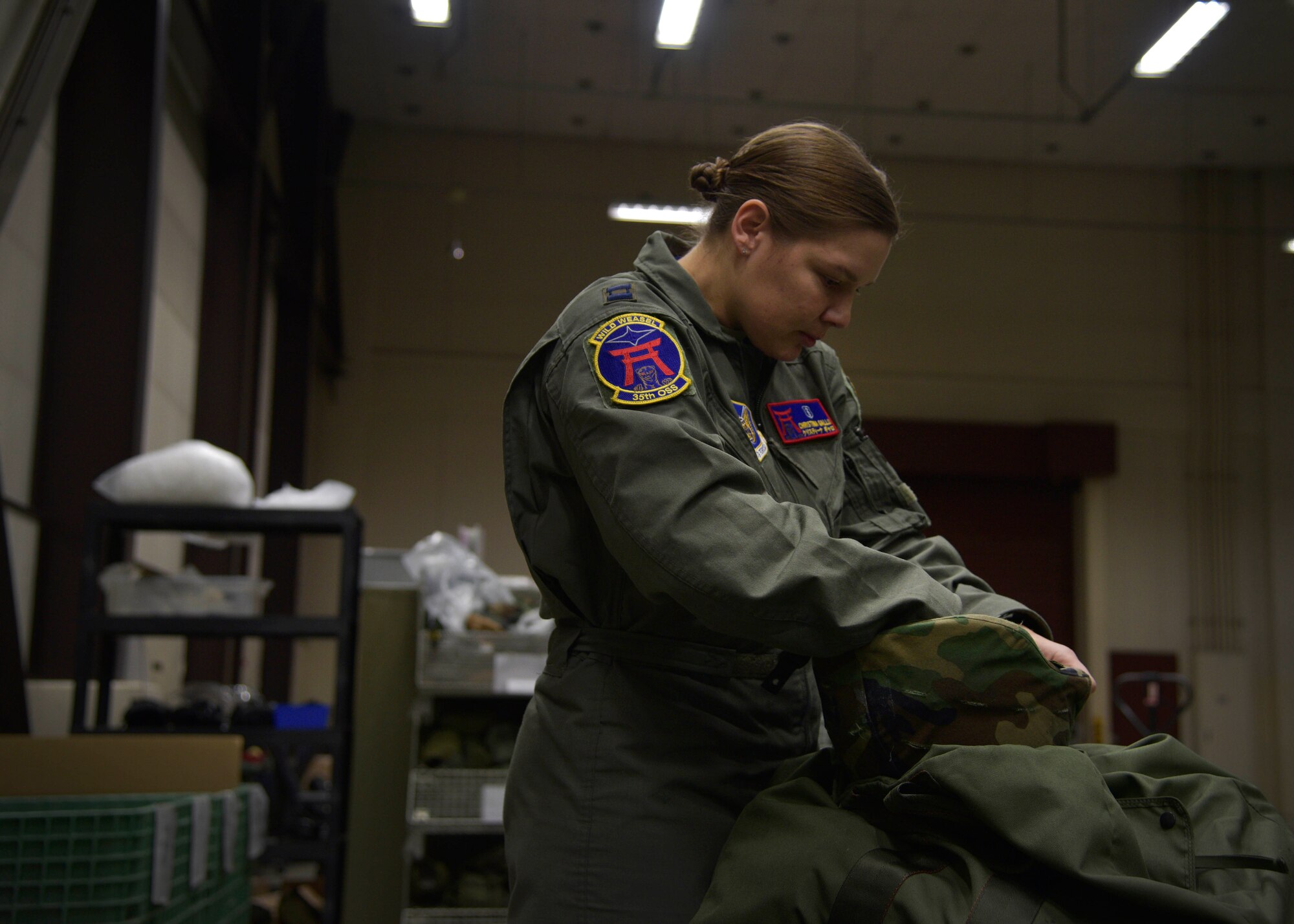 U.S. Air Force Capt. Christina Gallo, the Aircrew Flight Equipment Flight commander with the 35th Operations Support Squadron, inspects her helmet at Misawa Air Base, Japan, Jan. 6, 2016. IPE Airmen issue all in-processing active-duty members a training C-bag, consisting of a joint service lightweight integrated suit technology coat and trousers, flak vest, M50 gas mask, chemical boots, chemical gloves, glove inserts, web belt, canteen, helmet and suspenders. (U.S. Air Force photo by Senior Airman Deana Heitzman)
