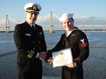 Petty Officer 2nd Class Cody Davis, right, a hospital corpsman serving at Naval Health Clinic Charleston, receives a Certificate of Reenlistment from Cdr. Richard Graham, director for NHCC's Clinical Support Services and department head of NHCC's laboratory, during Davis's reenlistment ceremony Dec. 11 aboard the USS Yorktown, located at Patriots Point Naval & Maritime Museum in Mount Pleasant. (Navy photo/Kris Patterson)