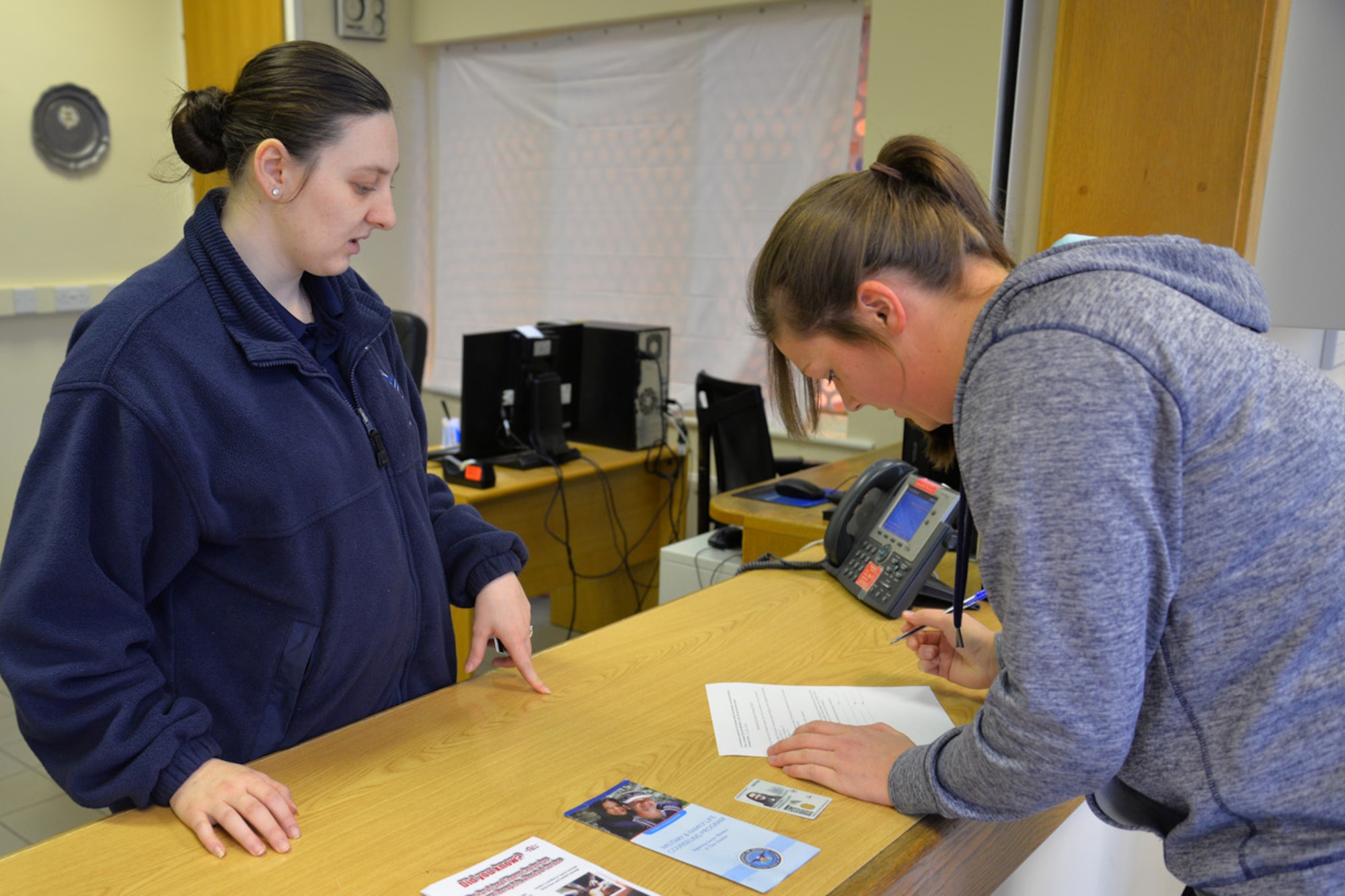 U.S. Air Force Airman Taylor Barnard, left, 100th Force Support Squadron fitness journeyman, talks U.S. Air Force Senior Airman Hope Kollauf, 100th Security Forces Squadron combined controller, through the registration process for the Northside Fitness Center’s fitness access program Jan. 7, 2016, on RAF Mildenhall, England. The program is being put into place Air Force-wide as facilities become unmanned. It gives members 24/7 access to the gym, enabling them to work out when they choose, even after hours, or on U.S. holidays and goal or family days. (U.S. Air Force photo by Karen Abeyasekere/Released)