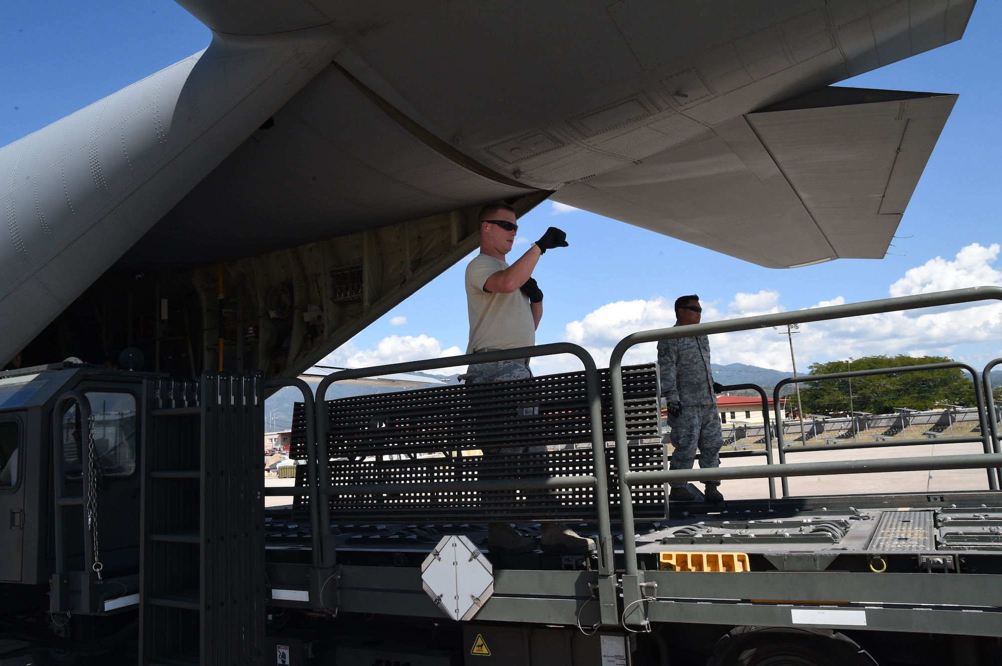 U.S. Air Force Staff Sgt. Dale Periman, 612th Air Base Squadron, gives directions to a driver while unloading cargo on Soto Cano Air Base, Honduras, Jan. 7, 2016. The cargo was delivered  by use of the Denton Program, a program created to allow donated humanitarian goods the ability to use space available on military cargo aircraft. (U.S. Air Force photo by Martin Chahin/Released)