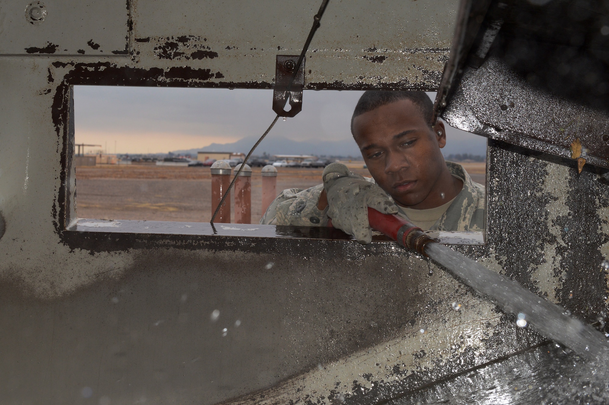 Airman 1st Class Demetrius Smith, 56th Civil Engineer Squadron heavy equipment operator, watches to make sure the interior gets clean while spraying out the street sweeper at Luke Air Force Base, Ariz., Jan. 5, 2016. (U.S. Air Force photo by Senior Airman James Hensley)
