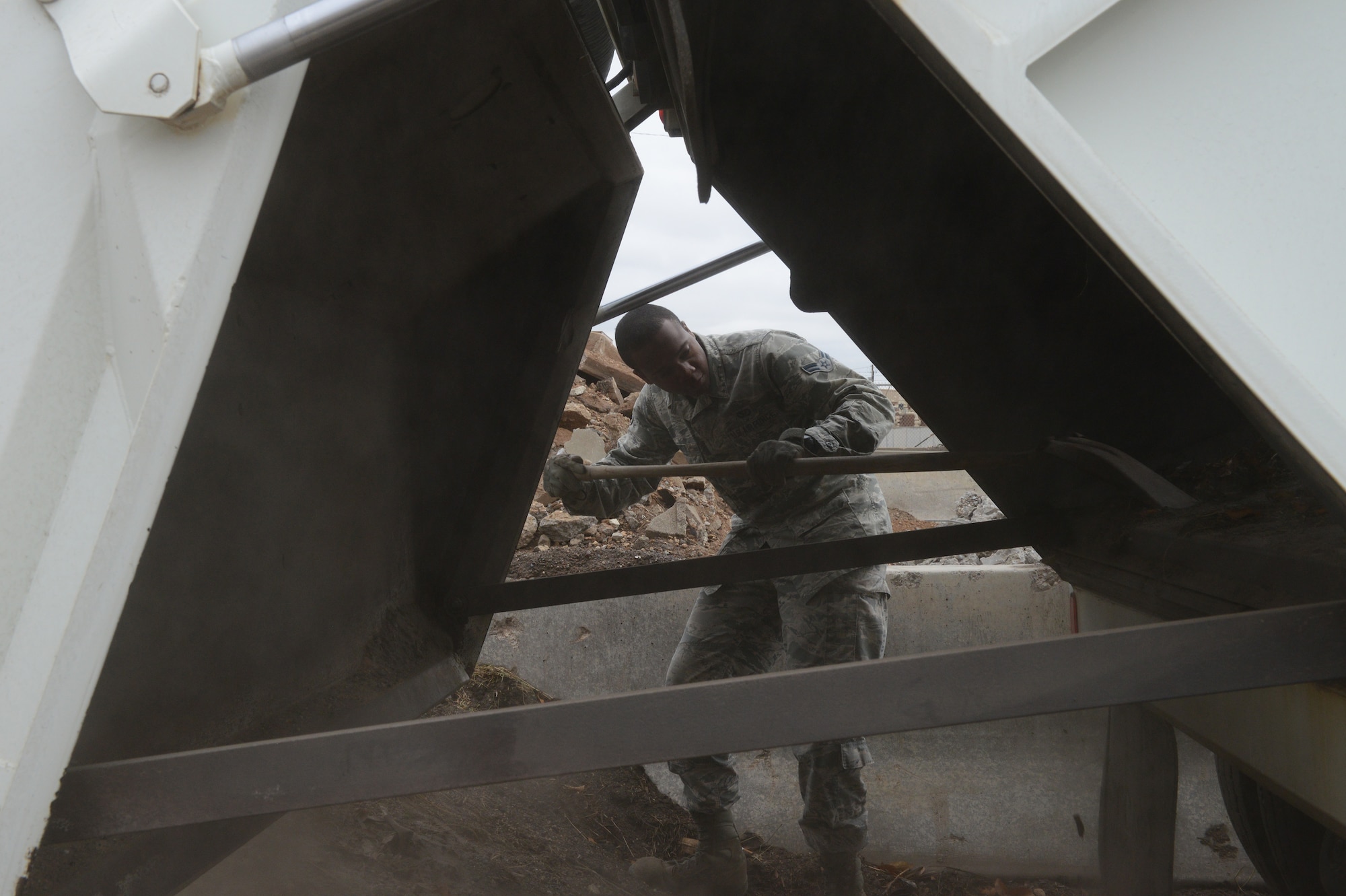 Airman 1st Class Demetrius Smith, 56th Civil Engineer Squadron heavy equipment operator, uses a shovel to get remaining foreign object debris out of the street sweeper at Luke Air Force Base, Ariz., Jan. 5, 2016. Smith had to ensure the street sweeper was empty prior to cleaning it. (U.S. Air Force photo by Senior Airman James Hensley)