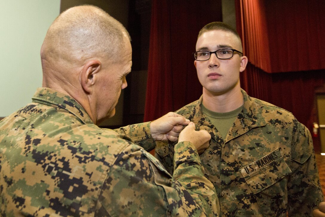 Commandant of the Marine Corps, Gen. Robert B. Neller, left, pins corporal rank insignia on Nathan S. Bolka with Headquarters Battalion, at Marine Corps Base, Hawaii, Nov. 20, 2015. Neller promoted Bolka from the rank of lance corporal during his Hawaii visit. (U.S. Marine Corps photo by Staff Sgt. Gabriela Garcia/Released)