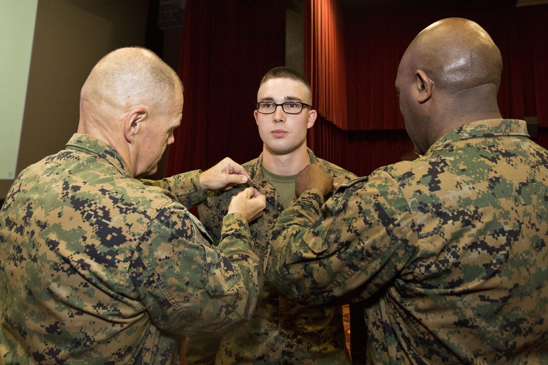 Commandant of the Marine Corps, Gen. Robert B. Neller, left, and Sgt. Maj. of the Marine Corps Ronald L. Green, right, pins corporal rank insignia on Nathan S. Bolka with Headquarters Battalion, at Marine Corps Base, Hawaii, Nov. 20, 2015. Neller promoted Bolka from the rank of lance corporal during their Hawaii visit. (U.S. Marine Corps photo by Staff Sgt. Gabriela Garcia/Released)