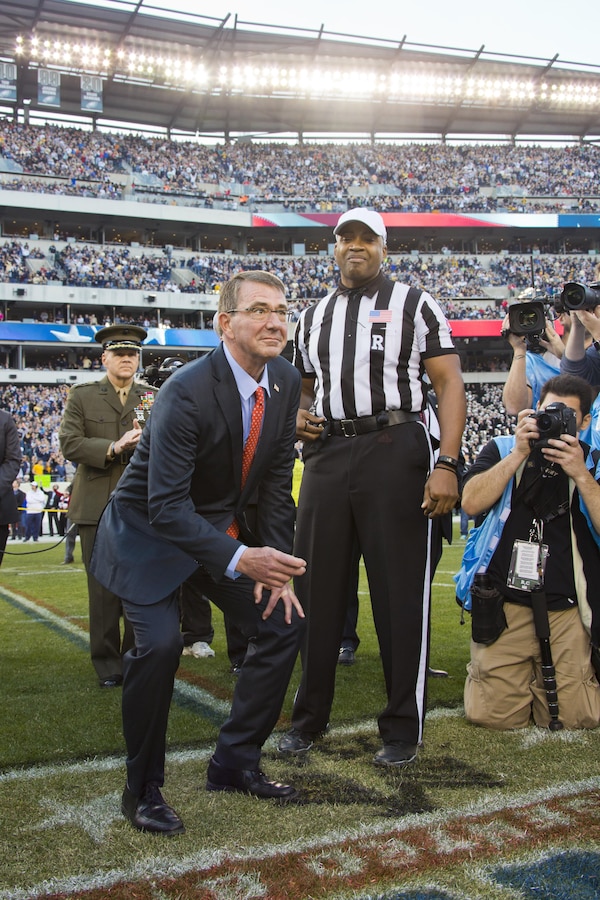 Commandant of the Marine Corps, Gen. Robert B. Neller, back left, watches Secretary of Defense, Ashton B. Carter, prepare for a coin toss at Philadelphia, Pa., Dec. 12, 2015. Neller participated in the Army-Navy game 's coin toss at Lincoln Financial Field. (U.S. Marine Corps photo by Staff Sgt. Gabriela Garcia/Released)