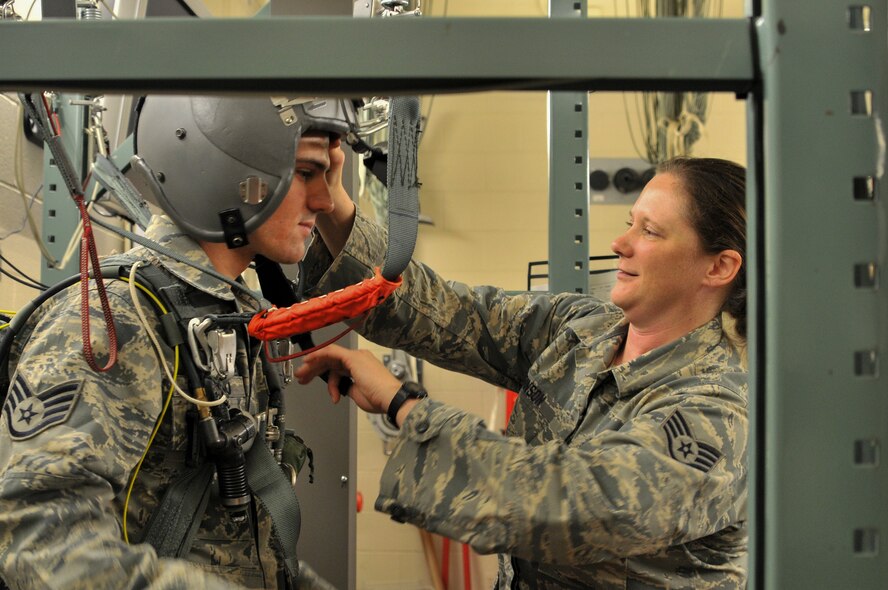 Staff Sgt. Kimberly Robinson, an aircrew flight equipment technician assigned to 911th Operations Support Squadron, straps Staff Sgt. Robert Guylitto into a parachute reality simulator at the Pittsburgh International Airport Air Reserve Station, Jan. 9, 2016. Robinson, formerly a 9-1-1 operator, has been a member of the Air Force since 2009. (U.S. Air Force photo by Airman Bethany Feenstra)